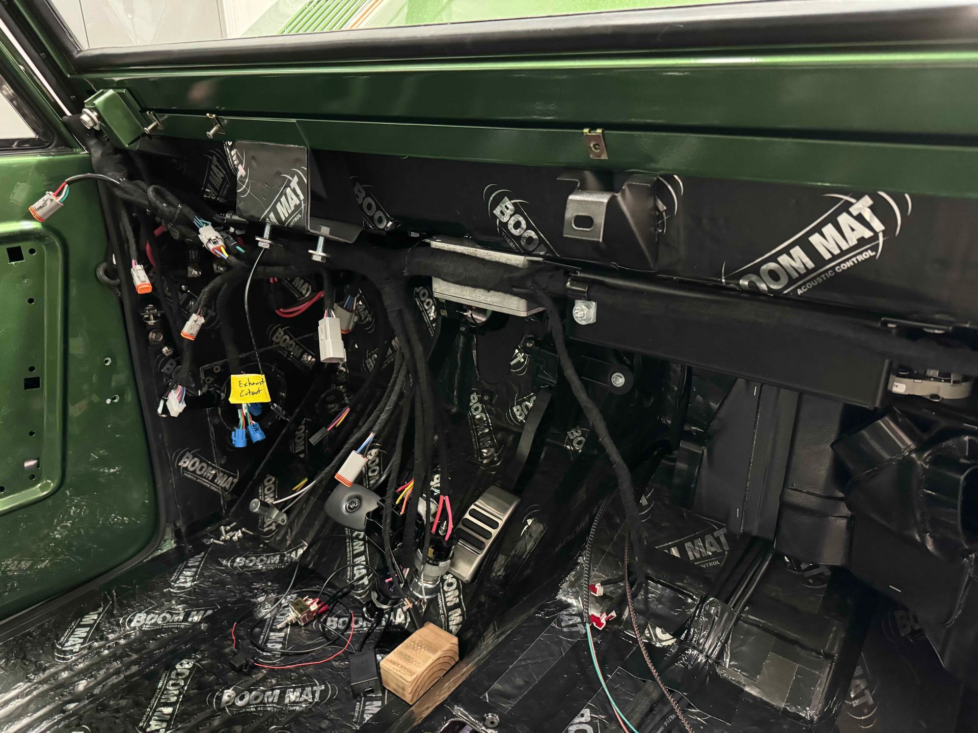 Close-up of a car’s stripped interior with exposed wiring, black panels, and a roll cage