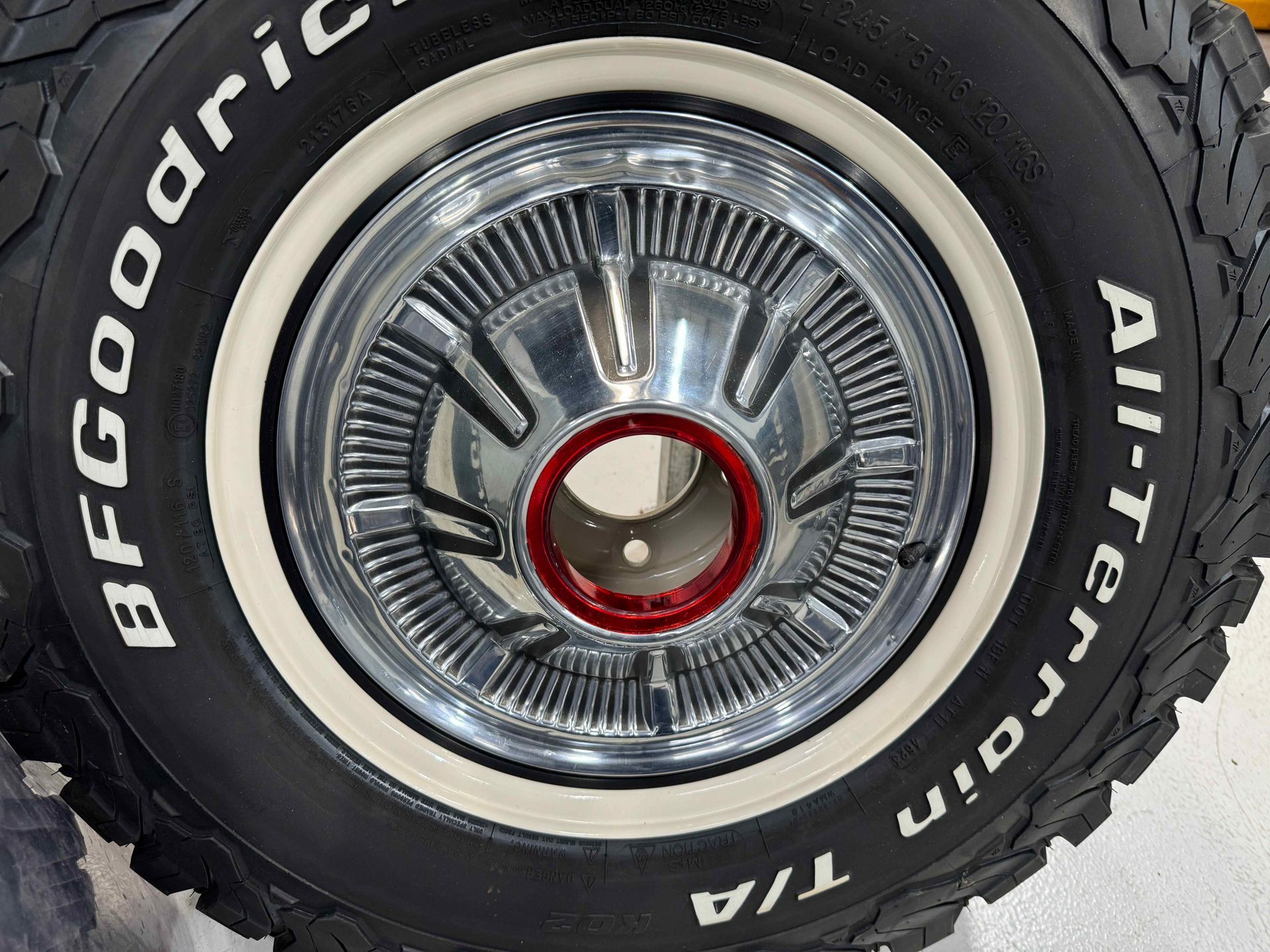 Close-up of a chrome wheel with a red center cap and Goodyear Wrangler tire lettering