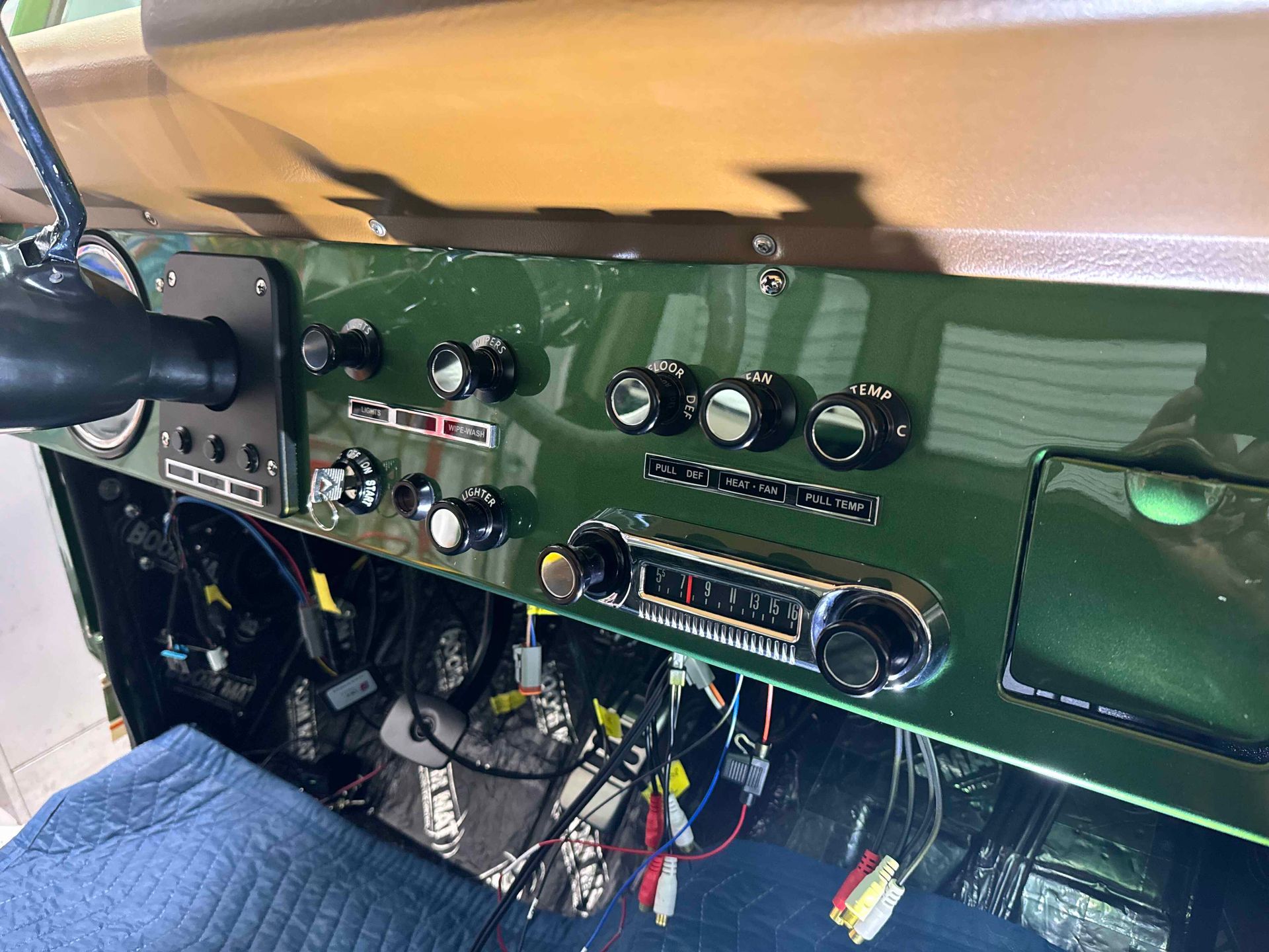 Classic car dashboard with green and beige panels, vintage radio, and knobs under the dash