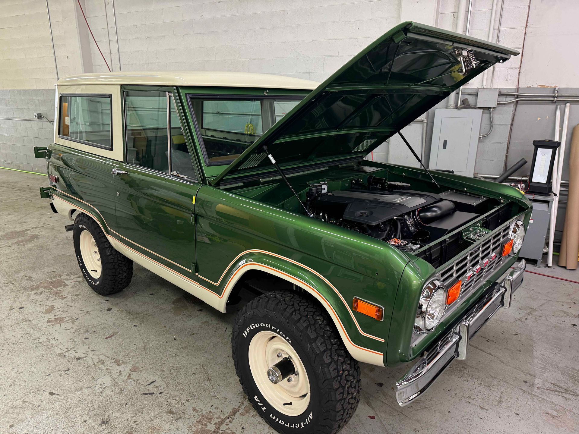 Green vintage Ford Bronco with hood open in a garage