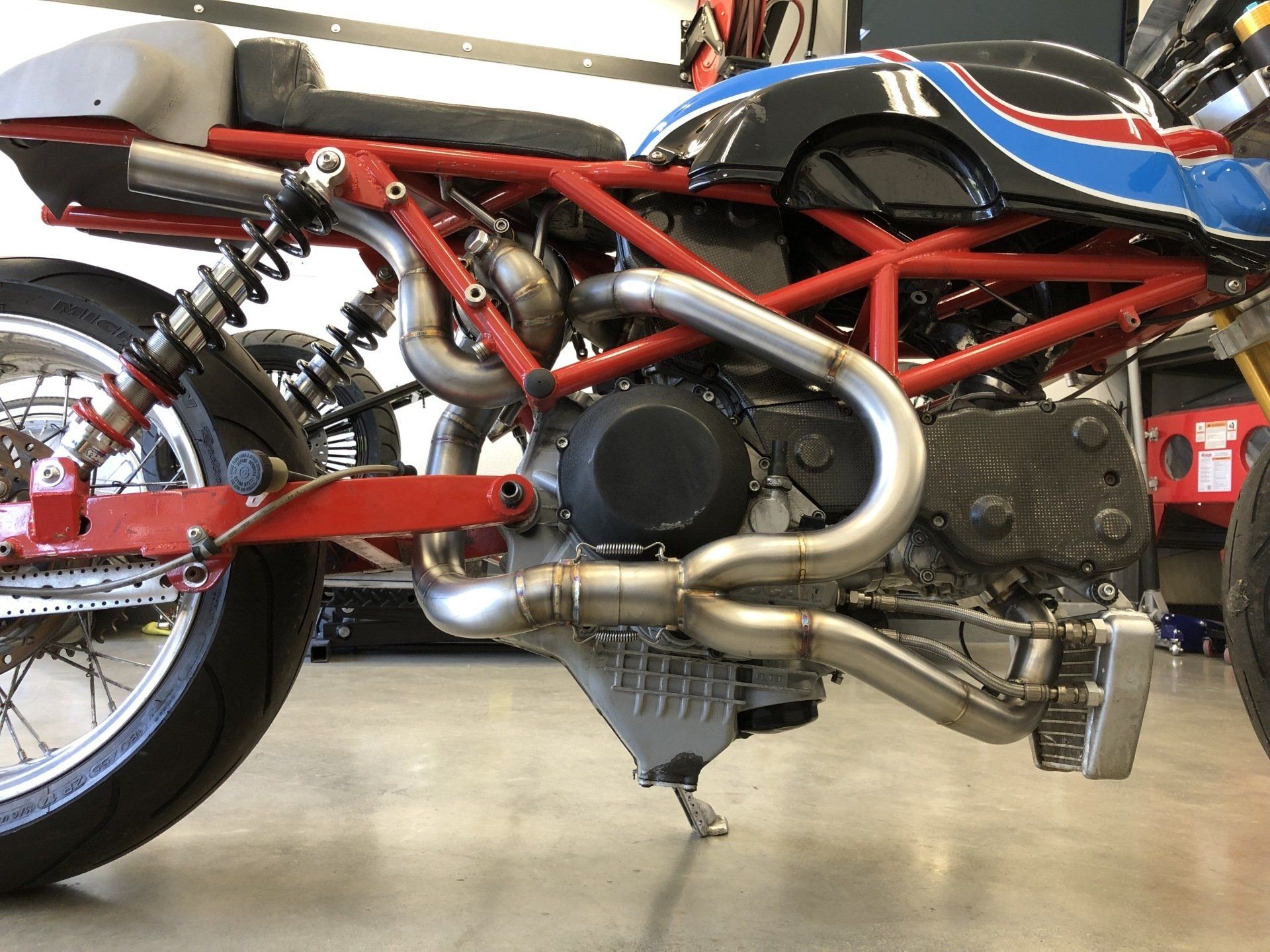 Side view of a red-and-blue custom motorcycle with exposed engine and red frame in a garage
