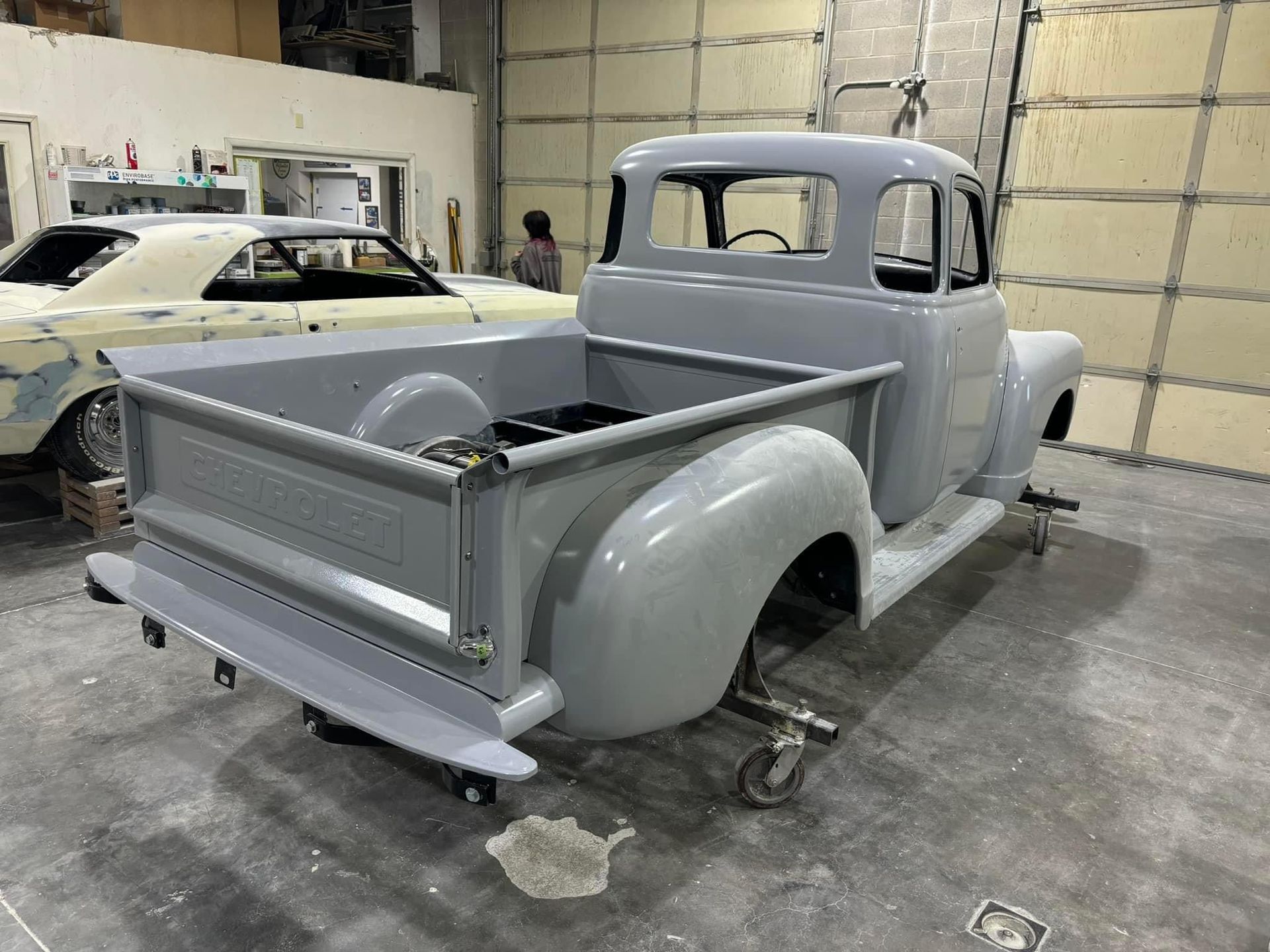 Gray classic pickup truck in a garage, partially restored with primer finish