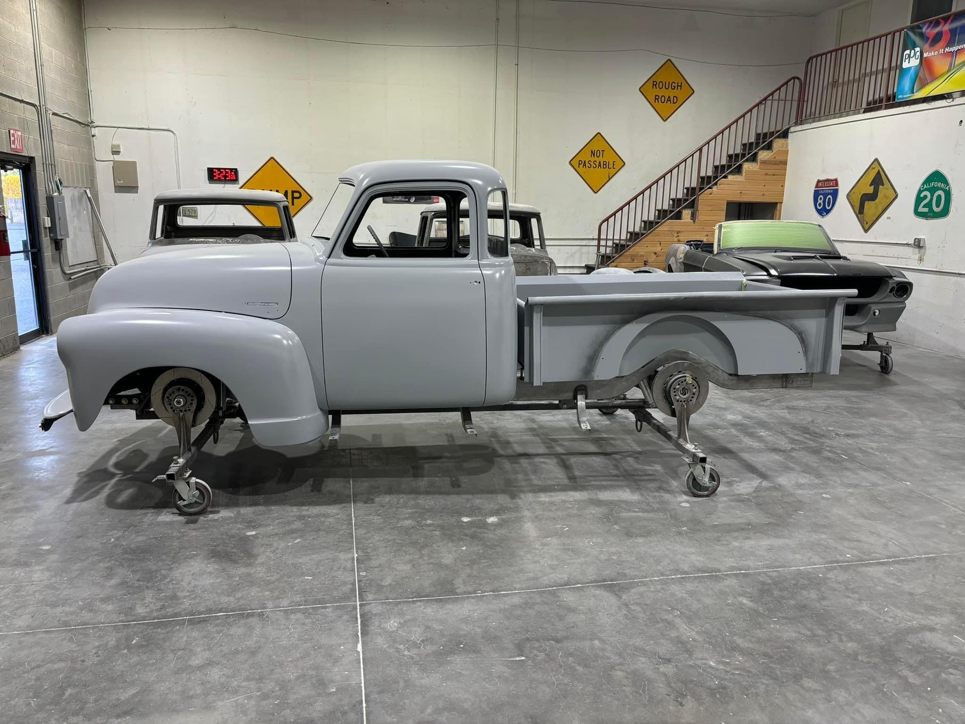 Vintage gray pickup truck in a workshop on jack stands with wheels removed