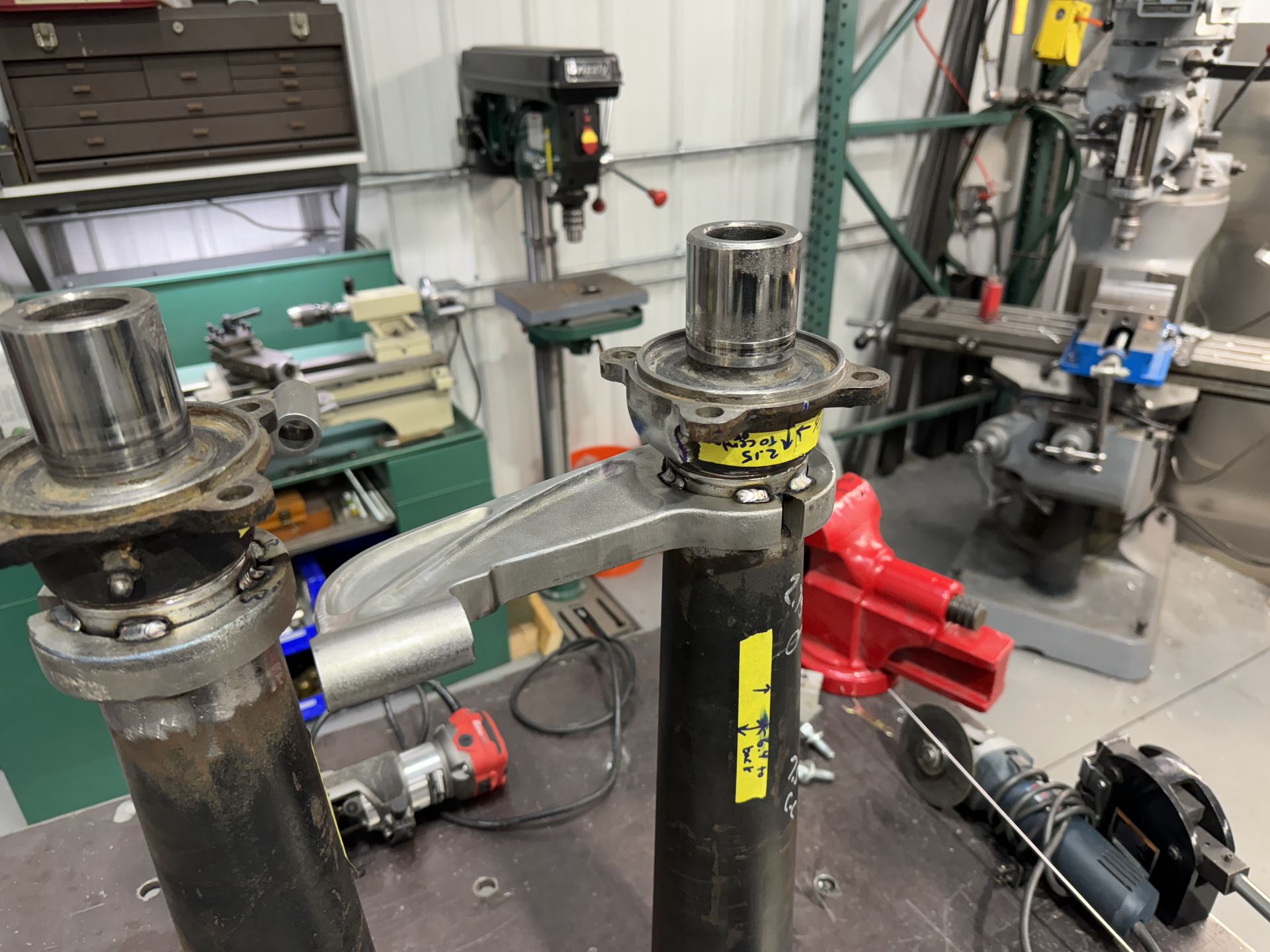 Industrial workshop with metal components, hoses, and a red pipe assembly on a workbench