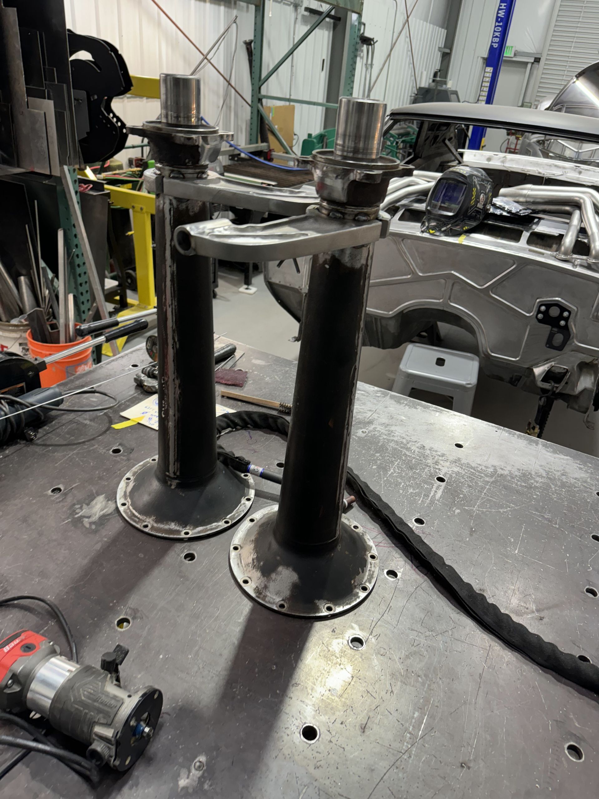 Industrial machinery with two black cylindrical posts on a metal platform in a workshop.