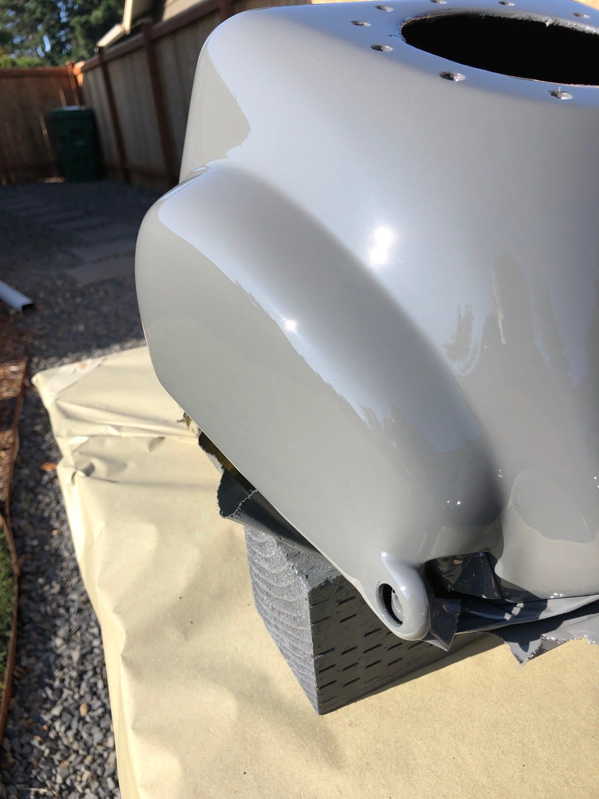 Glossy white motorcycle fairing or body panel resting outdoors on protective cardboard