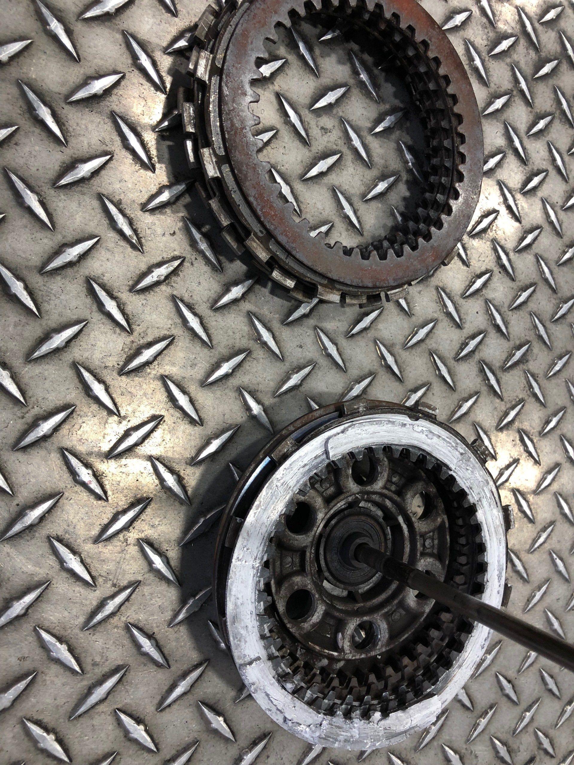 Two black gears on a silver diamond-plate metal surface, one partly covered in white residue.