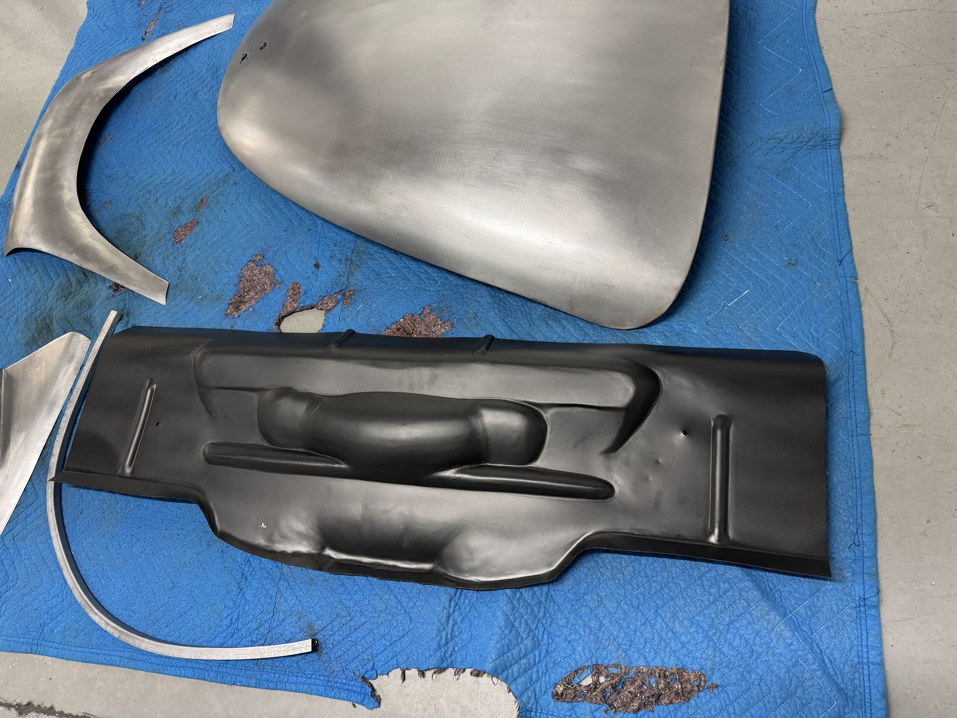 Car dashboard parts on a blue mat, including a black center panel and silver trim pieces
