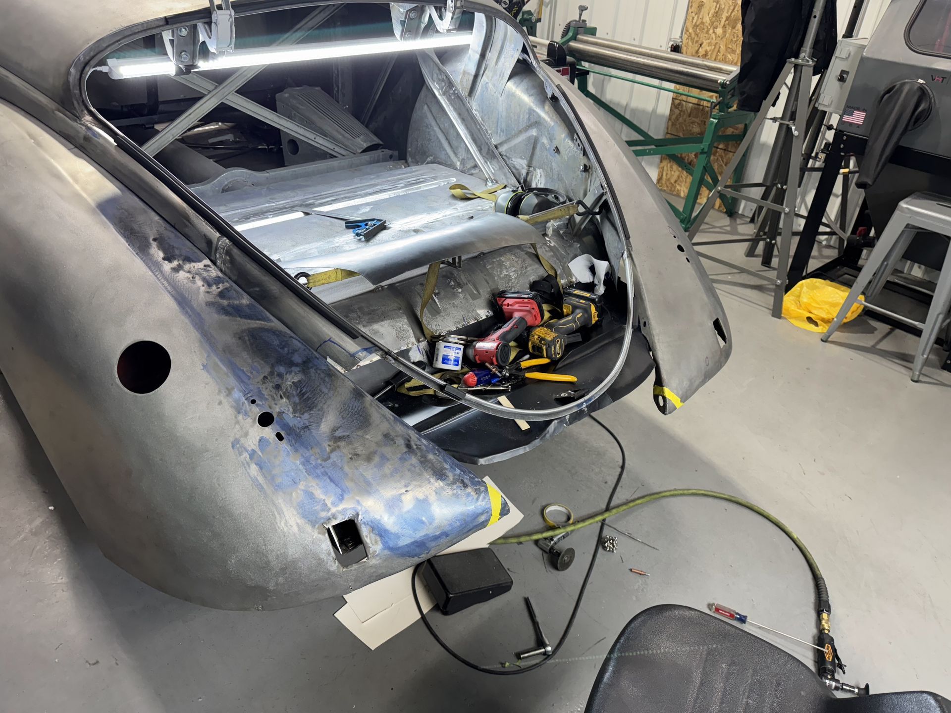 Damaged car rear body in a workshop, with exposed wiring and interior components visible