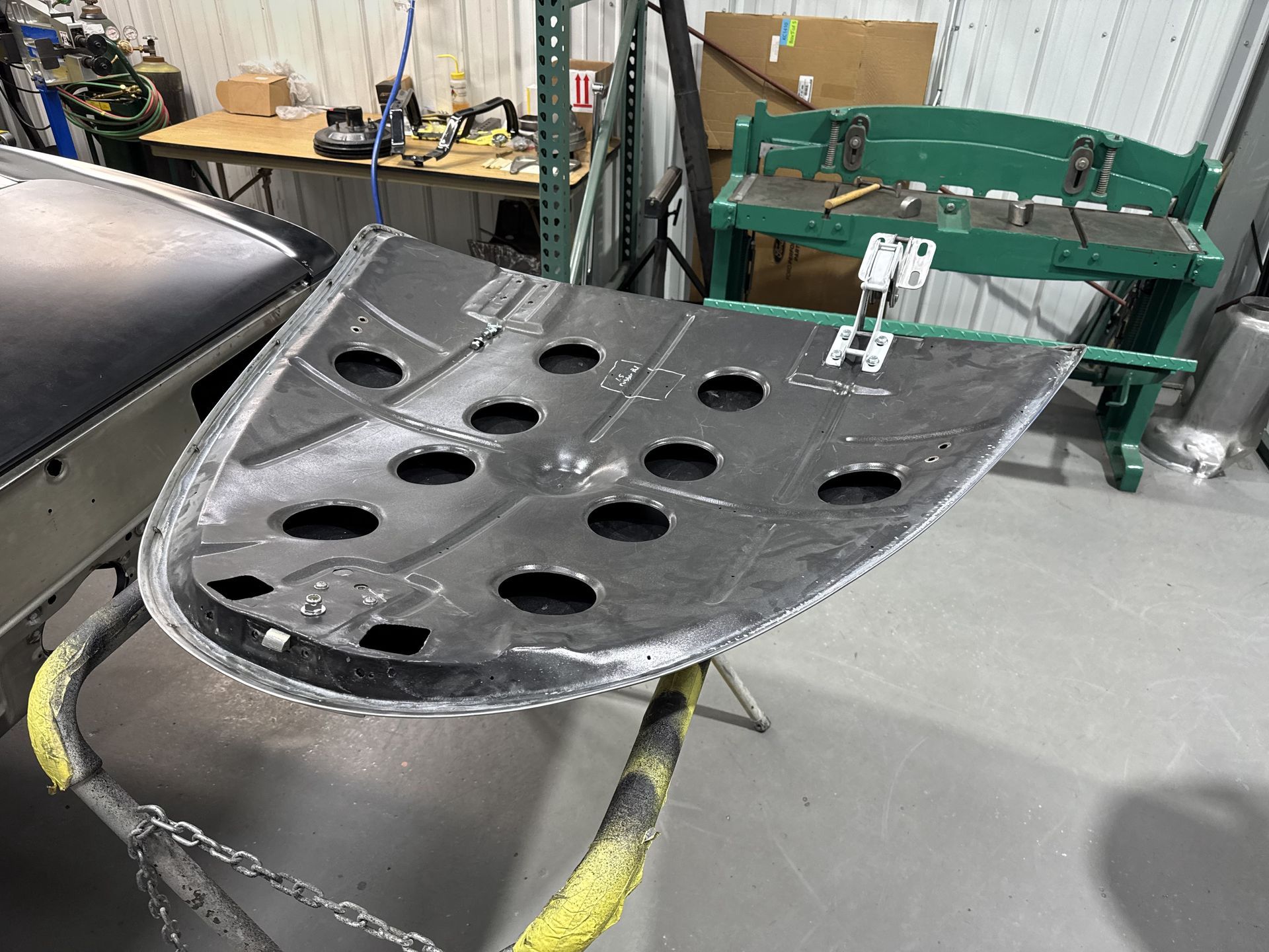 Bent, perforated black metal panel resting in an industrial workshop.