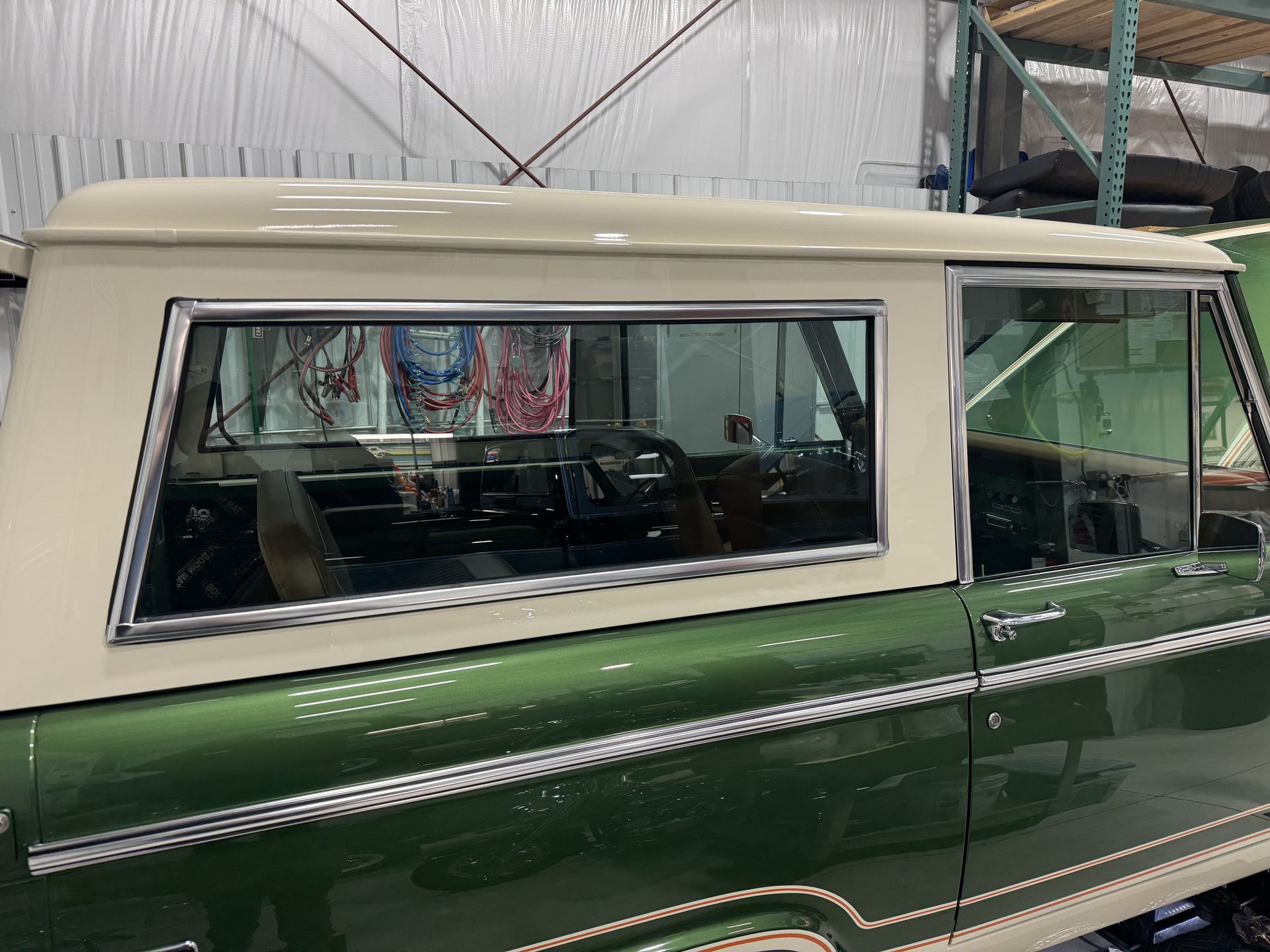 Green and white vintage SUV with a roof and large side windows parked indoors.