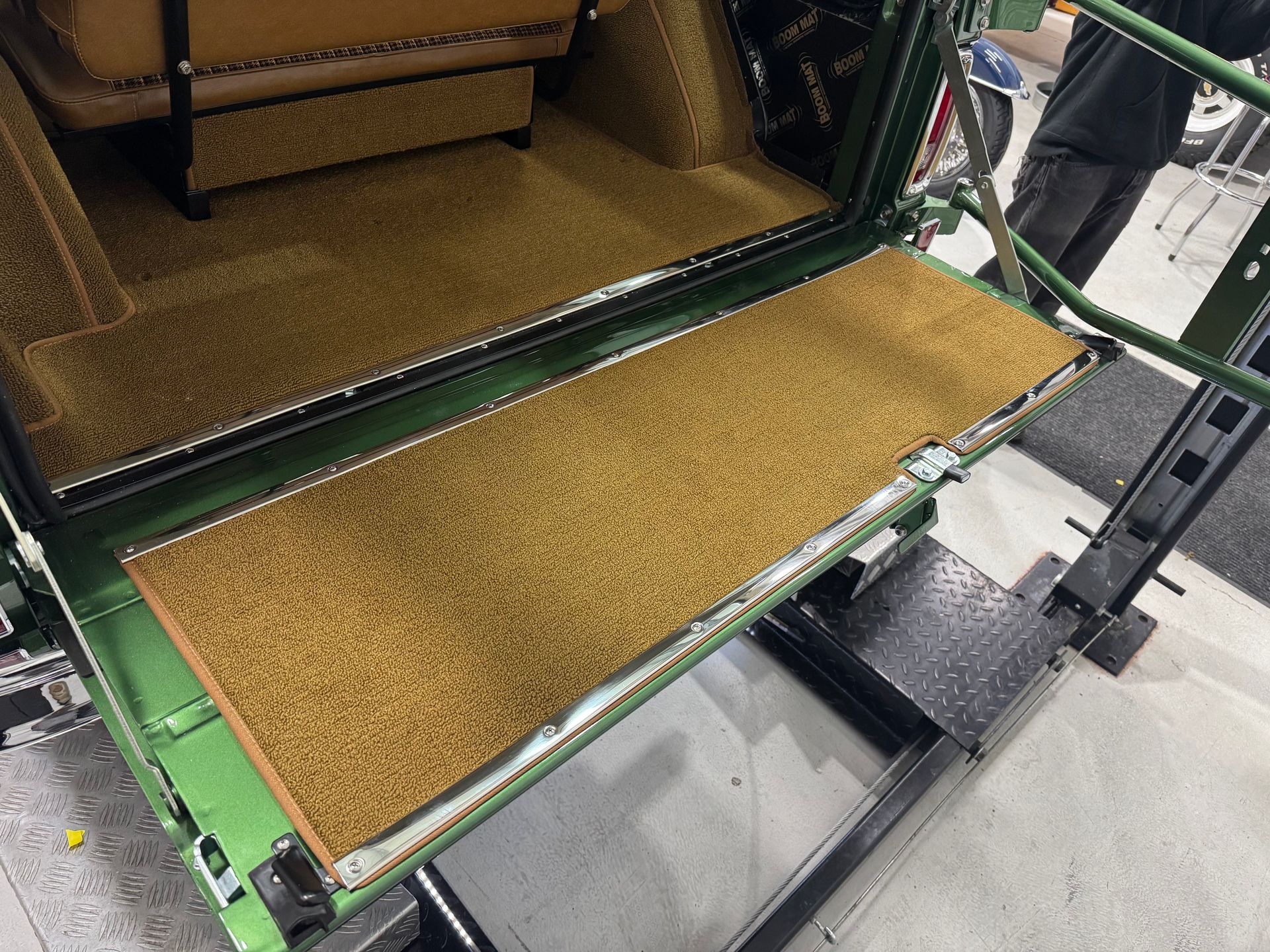 Green industrial conveyor with tan material on the belt in a factory setting