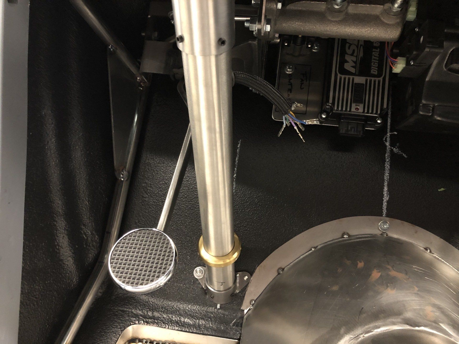 Mechanical interior with metal rods, pedal, and a large rounded housing inside a dark machine compartment