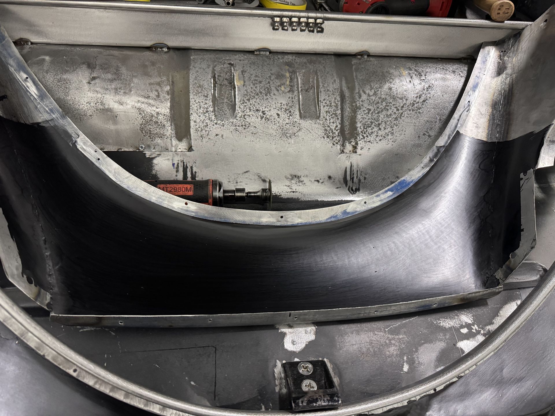 Black plastic vehicle interior panel with a large curved cutout and two exposed mounting clips, dusty and worn