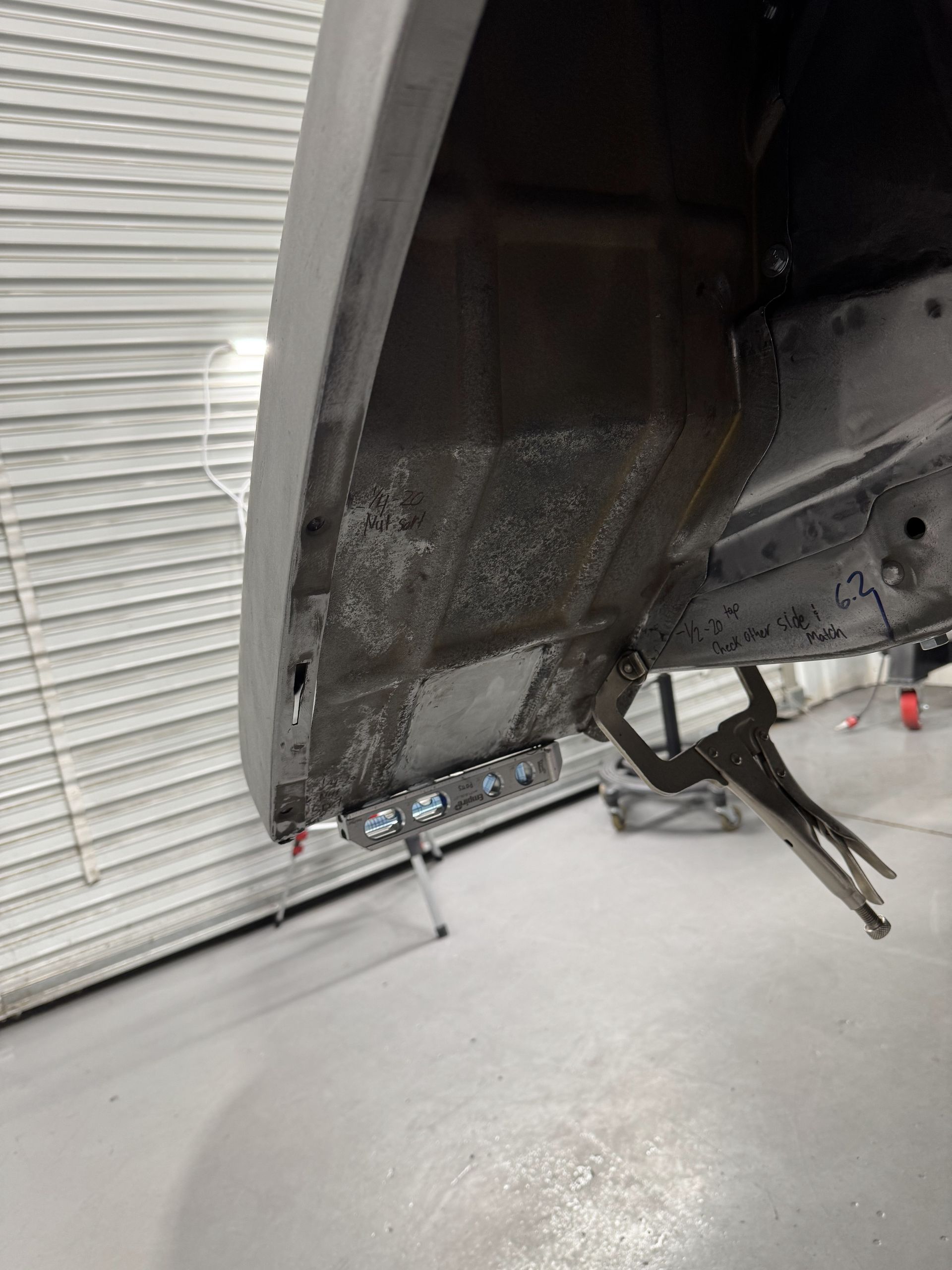 Close-up of a damaged aircraft fuselage near a hangar wall, with exposed dark interior and landing gear visible