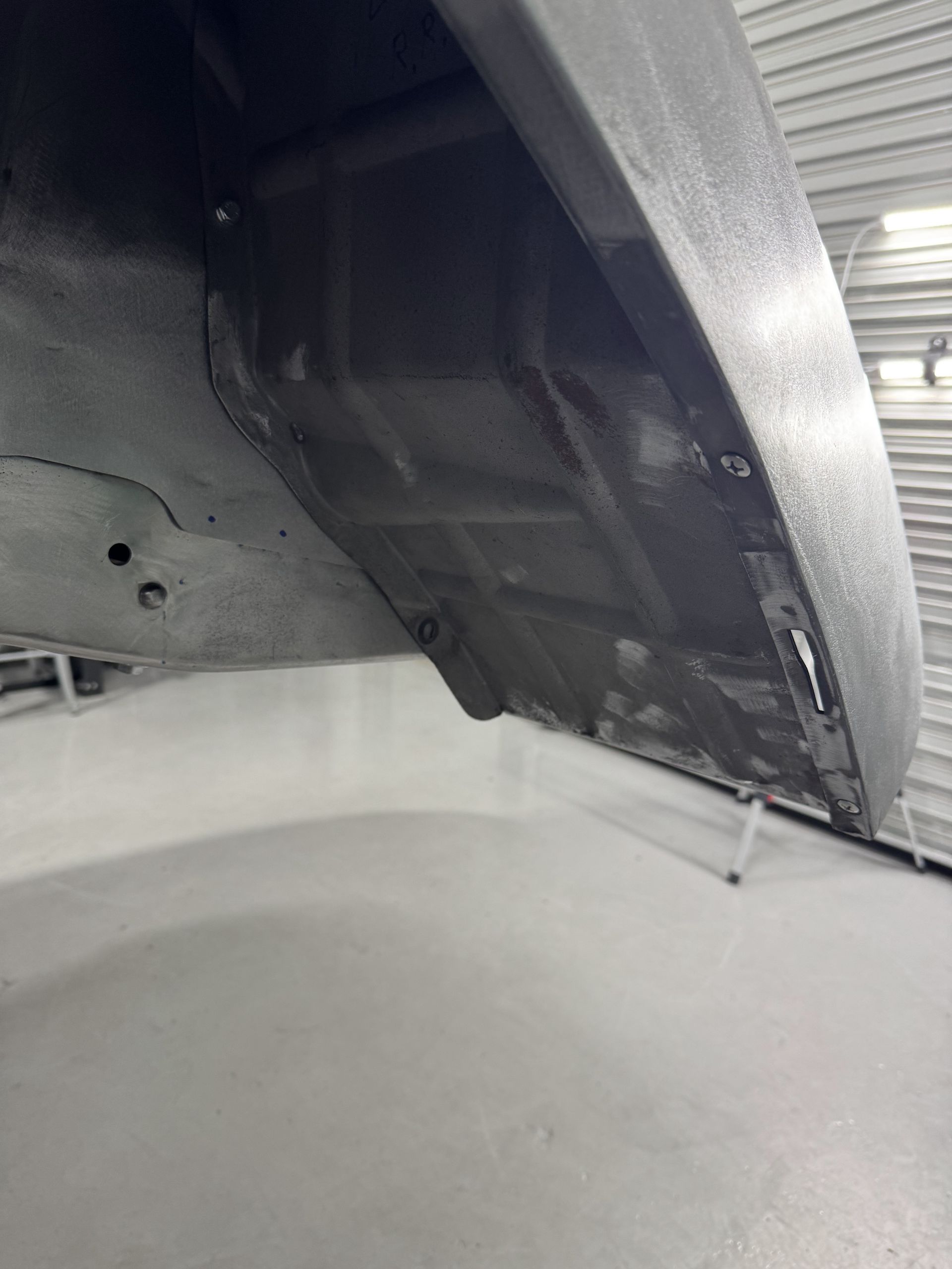 Close-up of a black metal underside with snow piled beneath and along the edge