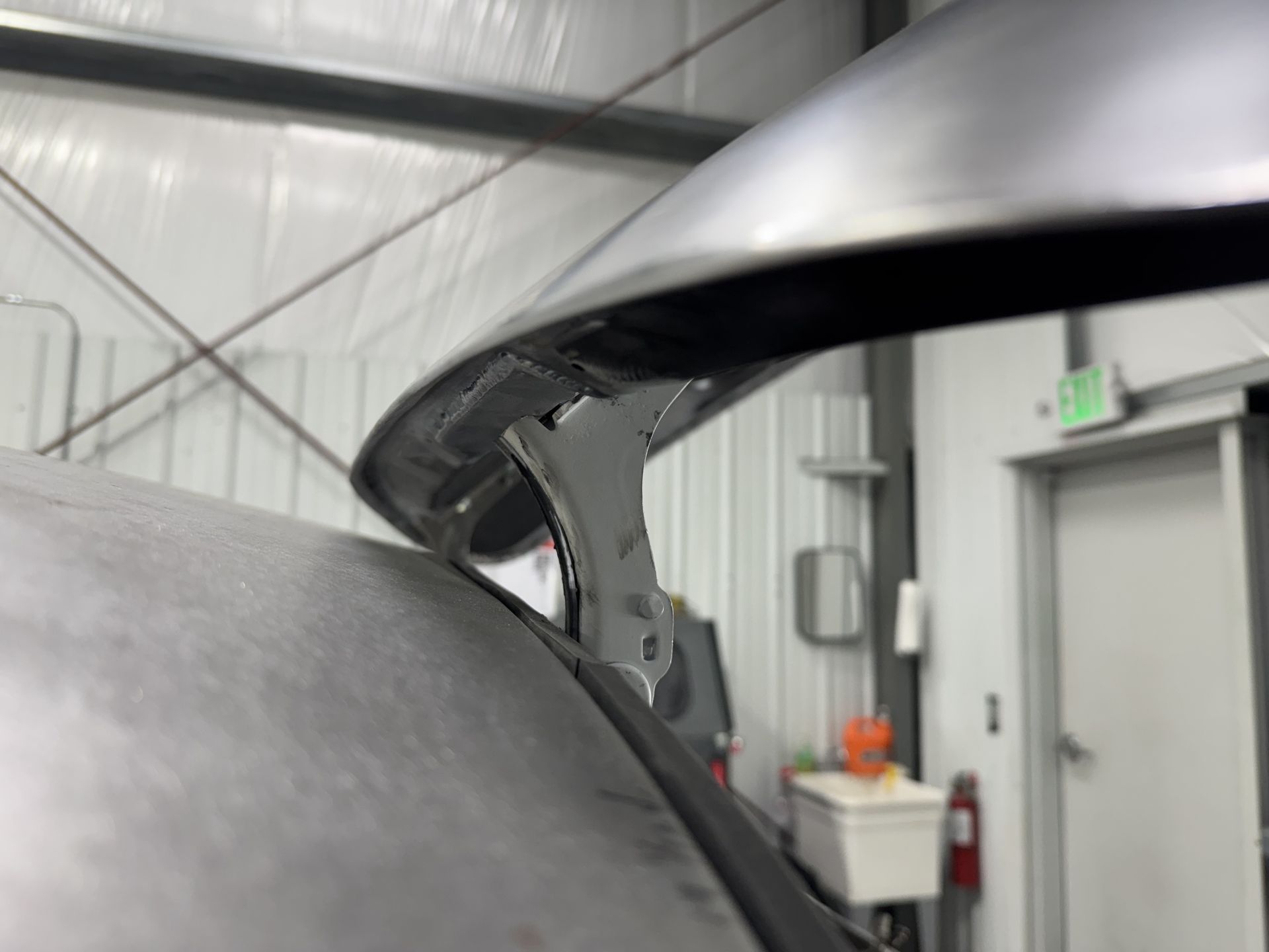 Close-up of a silver car panel being adjusted in an indoor workshop