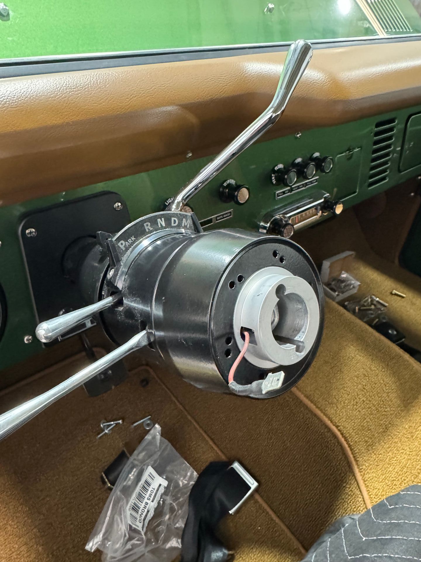 Classic car dashboard with a large chrome steering column and tan interior.