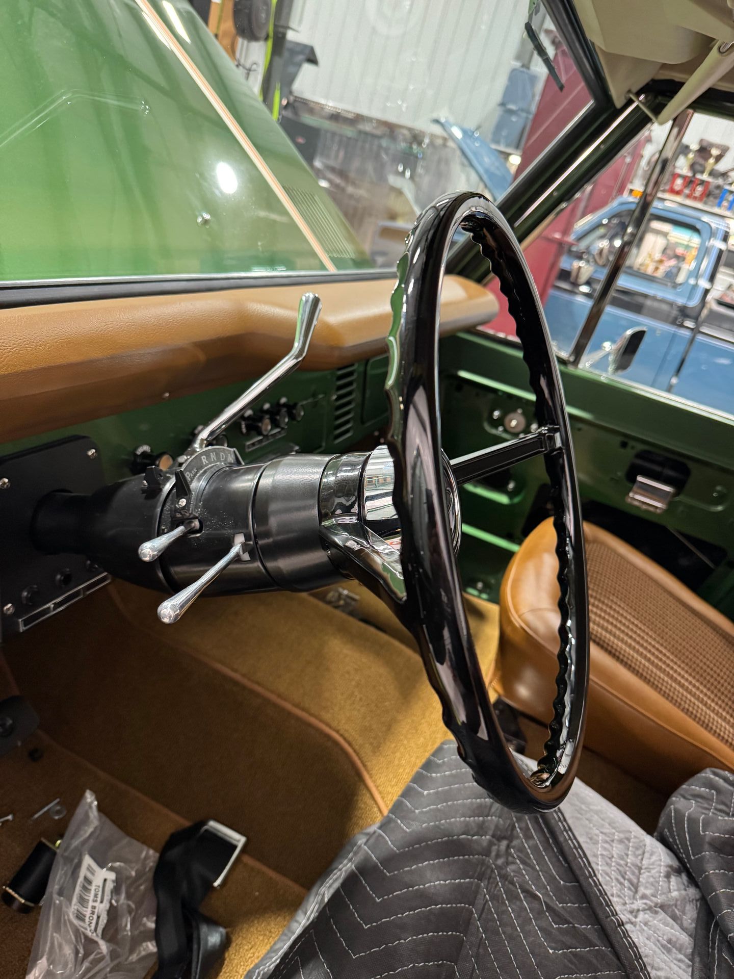 Classic car interior with a green dashboard, tan seats, and a black steering wheel.