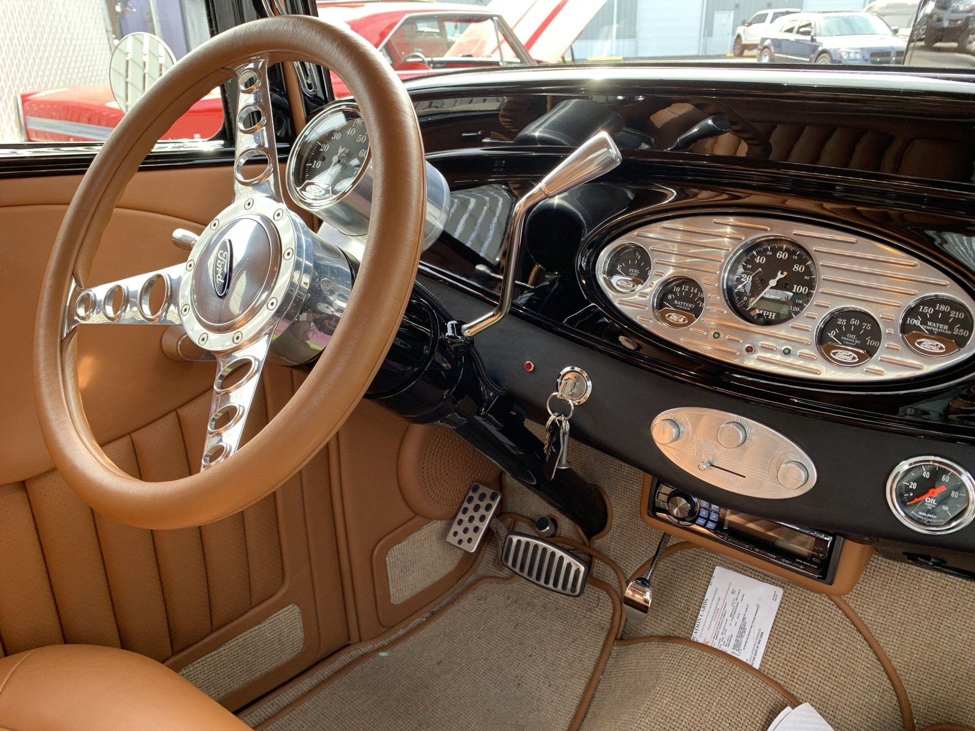Tan leather classic car interior with wood steering wheel and chrome dashboard gauges