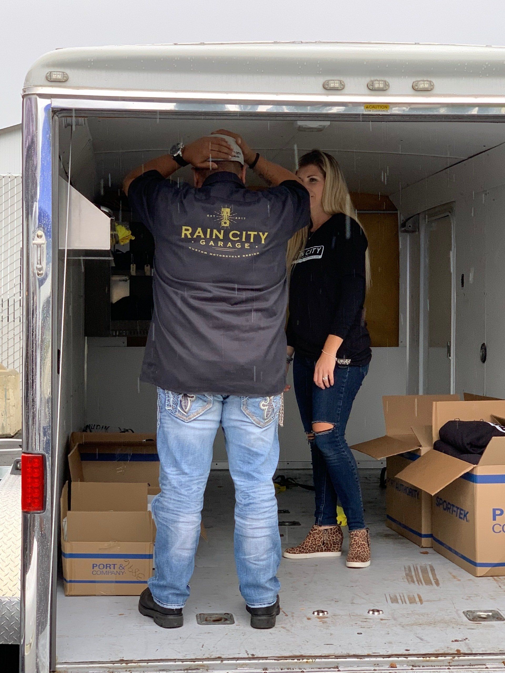 Two people unloading cardboard boxes from a moving truck.