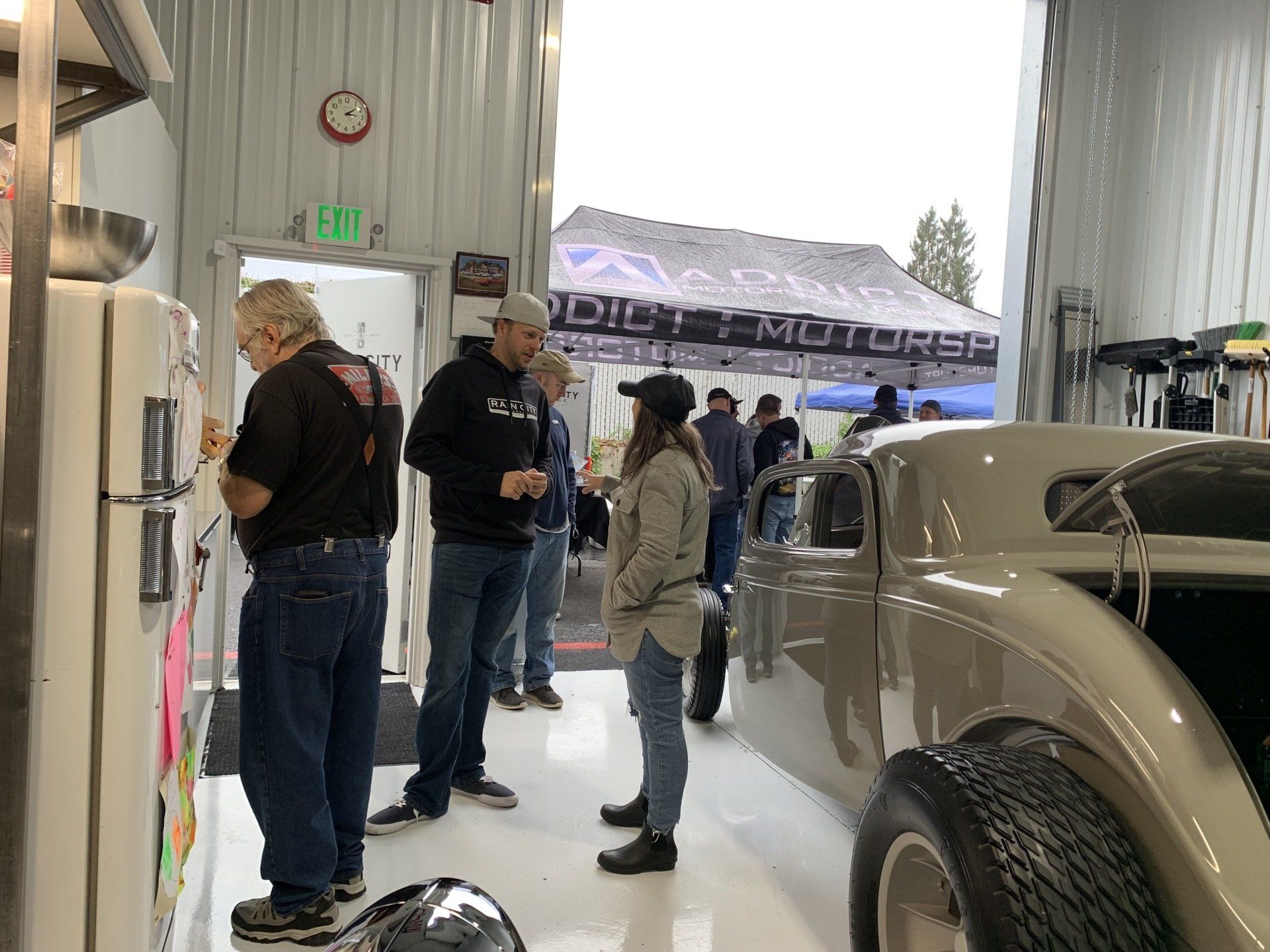 People standing beside a vintage car in a bright garage or showroom.