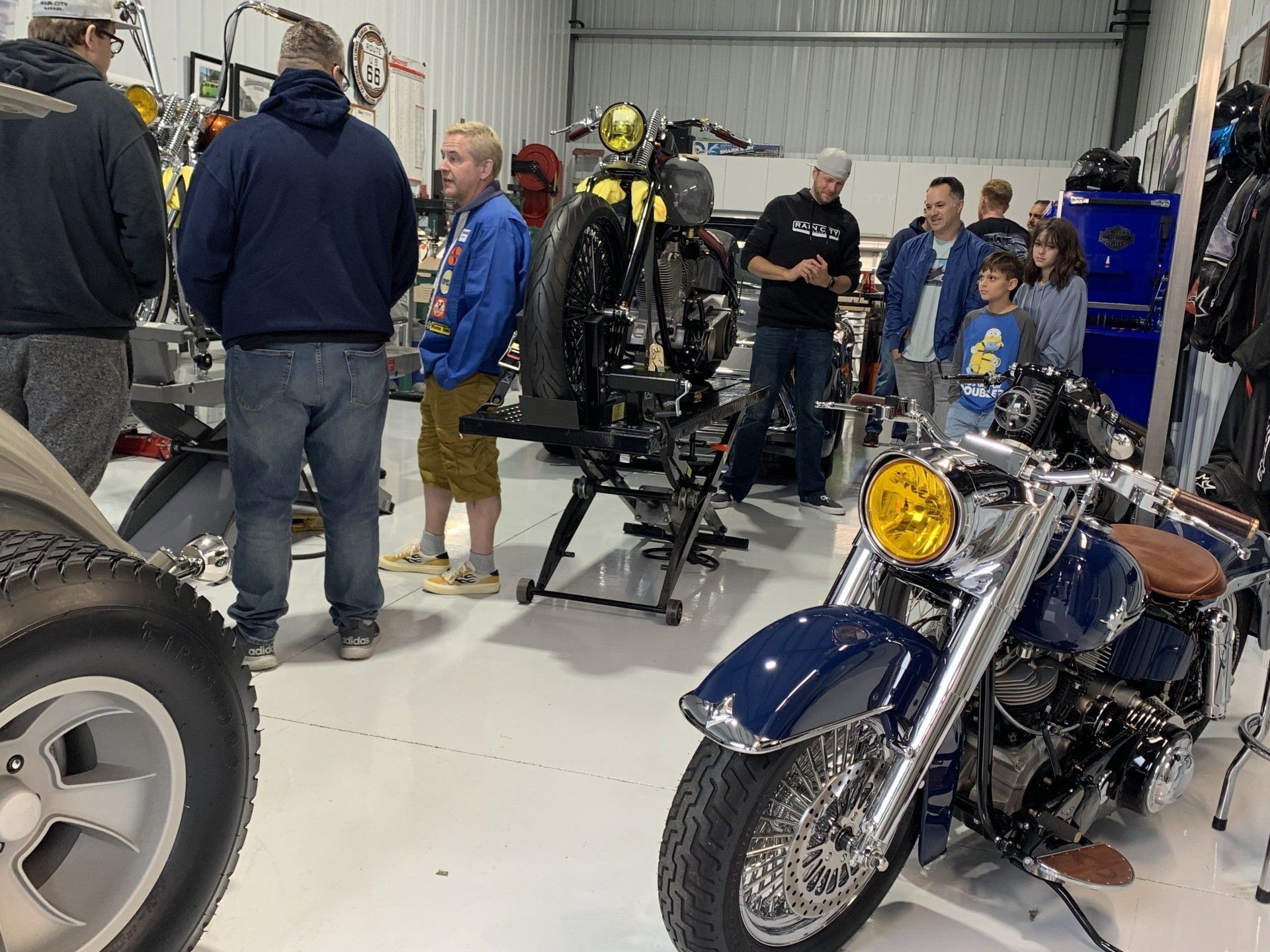People gathered around custom motorcycles in a garage workshop