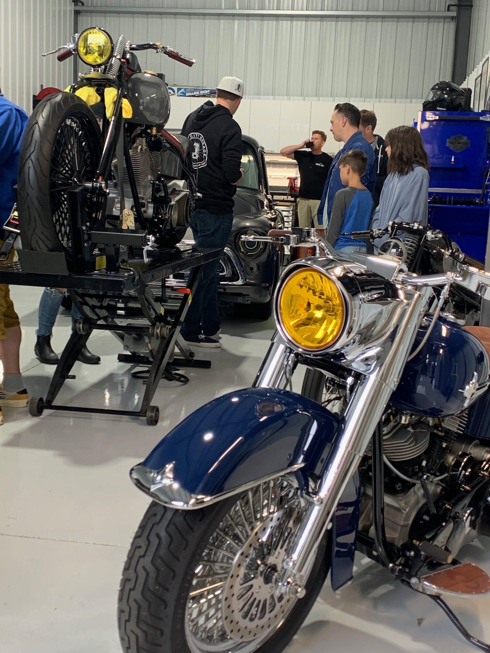 Classic motorcycles on display at an indoor event, with people gathered around them.