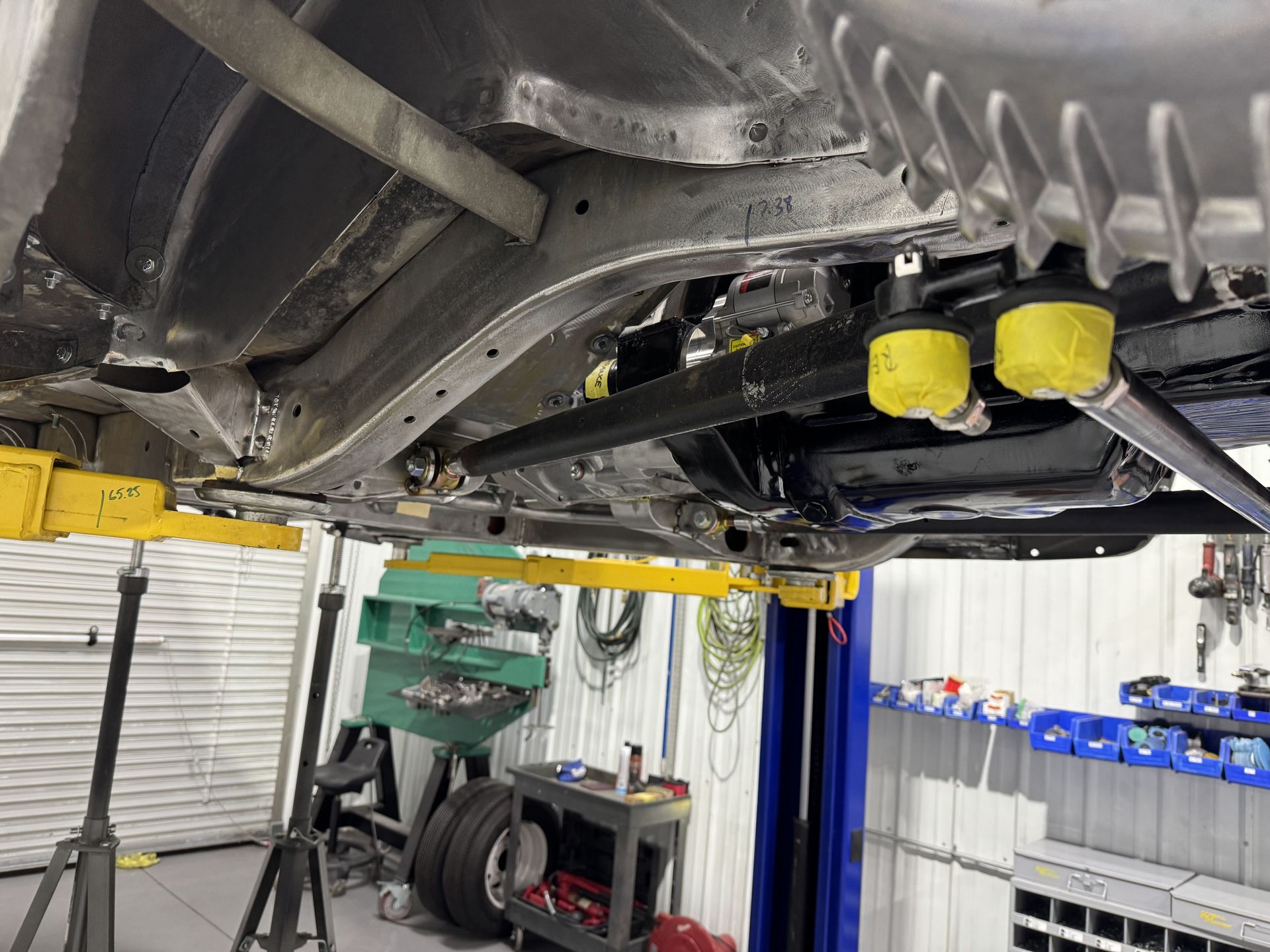 Undercarriage of a car on a lift in an auto shop, with two yellow oil filters visible.