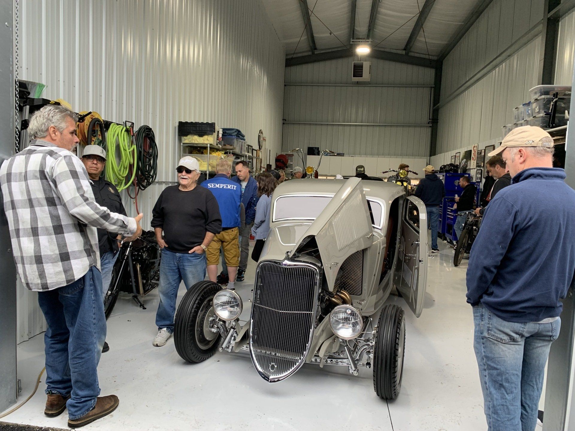 Vintage race car on display in a warehouse, surrounded by people looking at it.