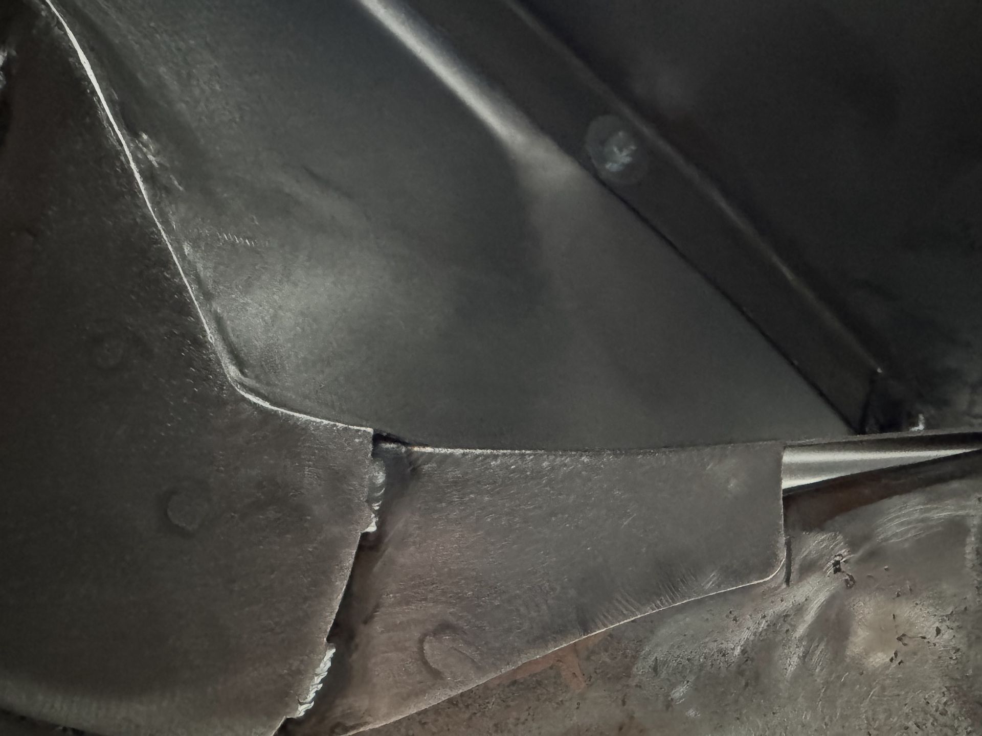 Close-up of black leather upholstery with a visible seam and metal rod inside.