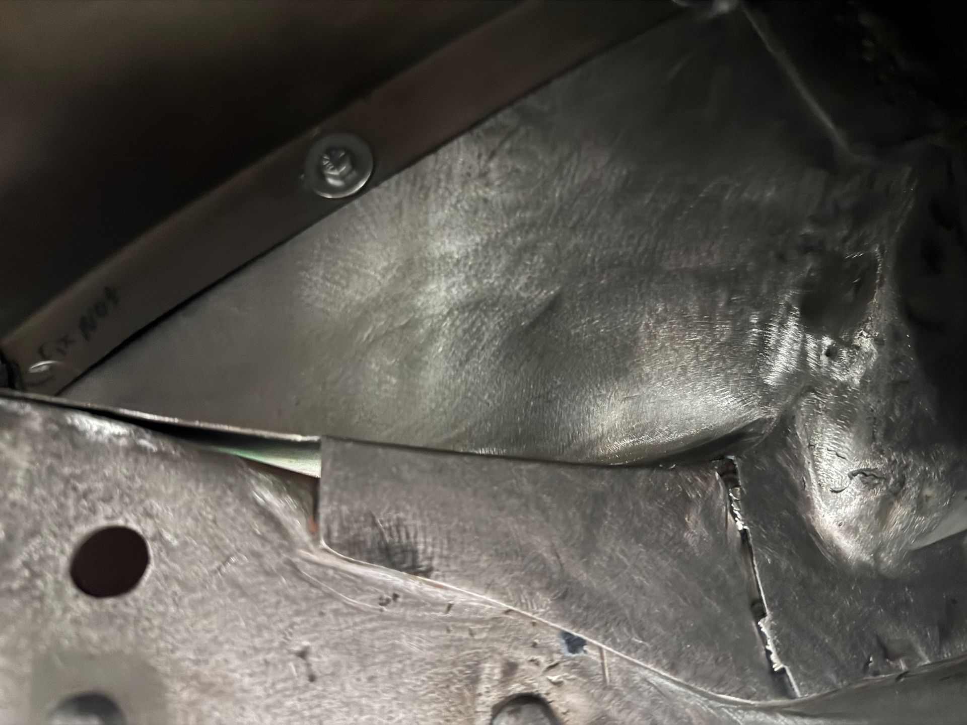 Close-up of a black strap and shiny crumpled material on a silver metal surface with a screw hole