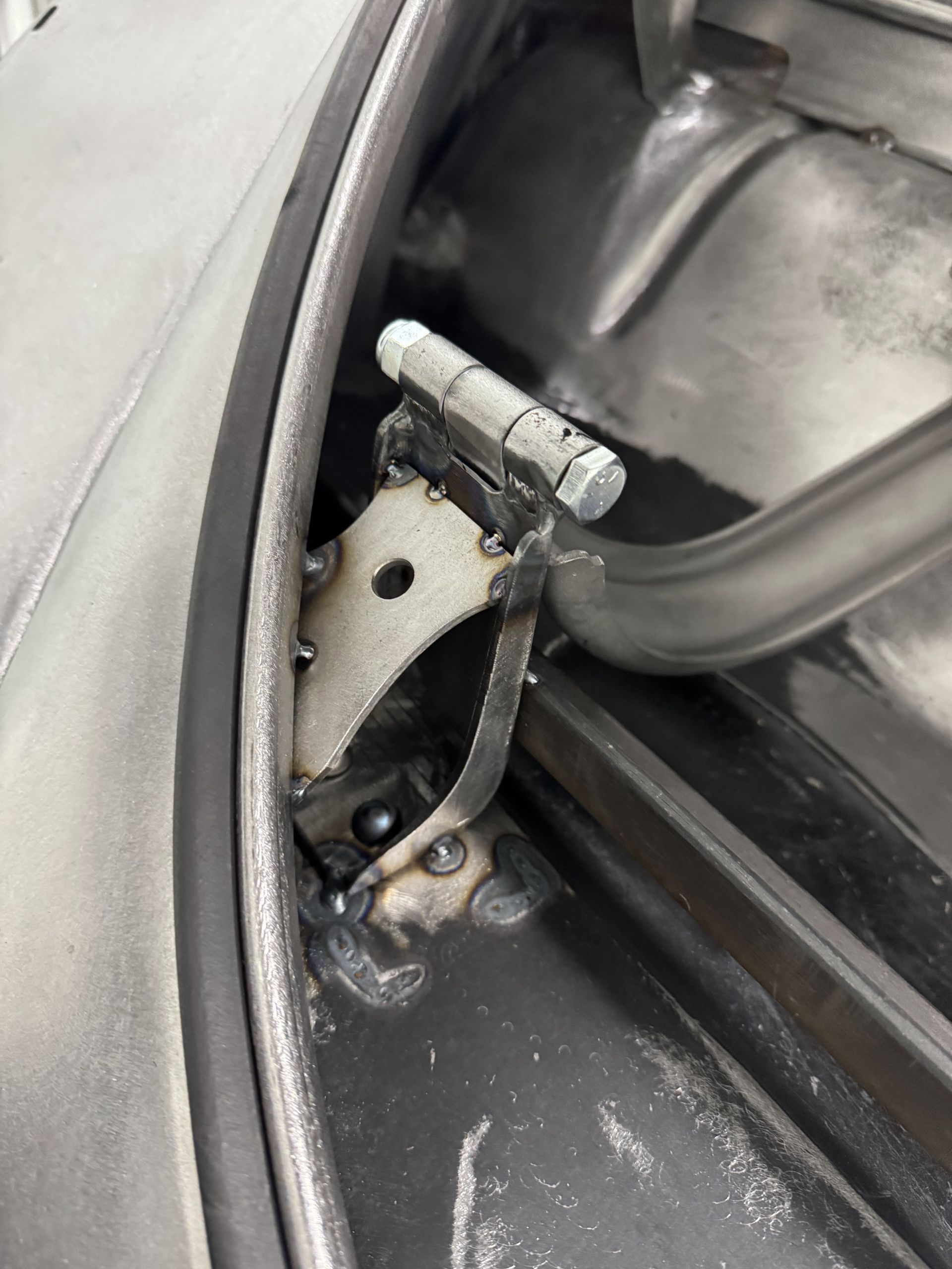 Close-up of a car door hinge and latch mechanism with exposed metal parts inside the door frame