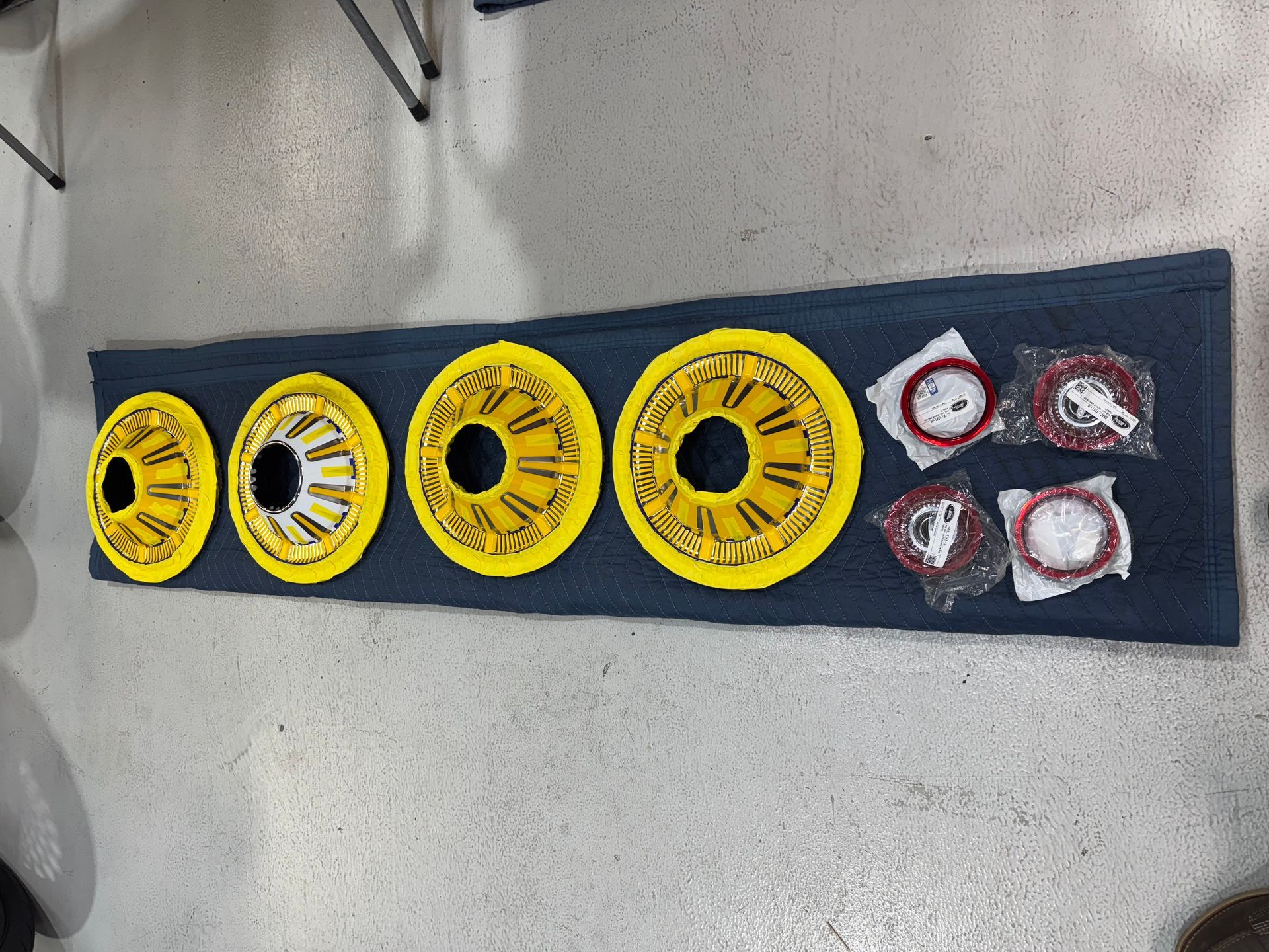 Yellow and red circular parts arranged on a dark mat on a gray floor