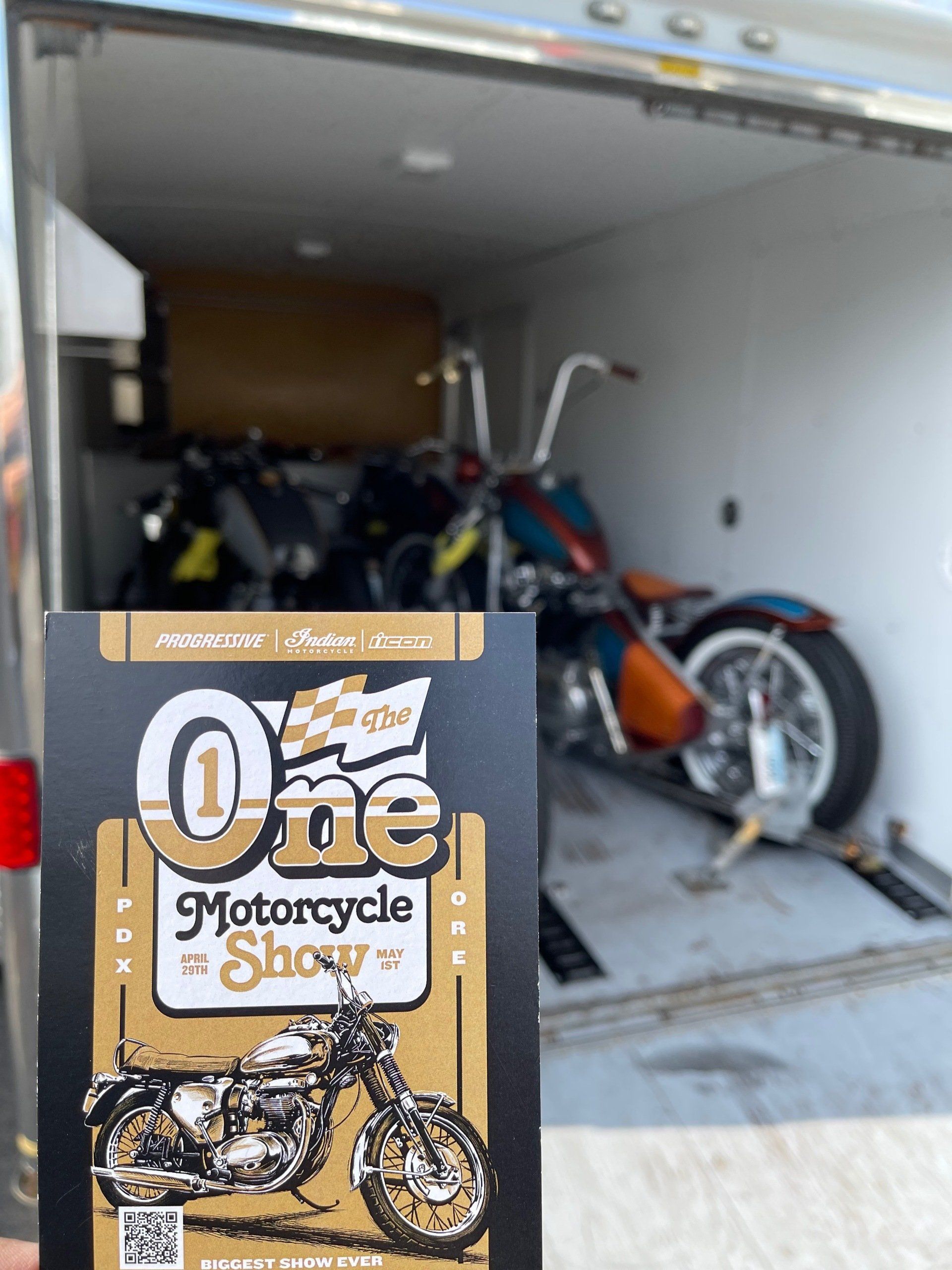 Motorcycle service flyer in front of a white cargo van holding a blue and orange motorcycle inside