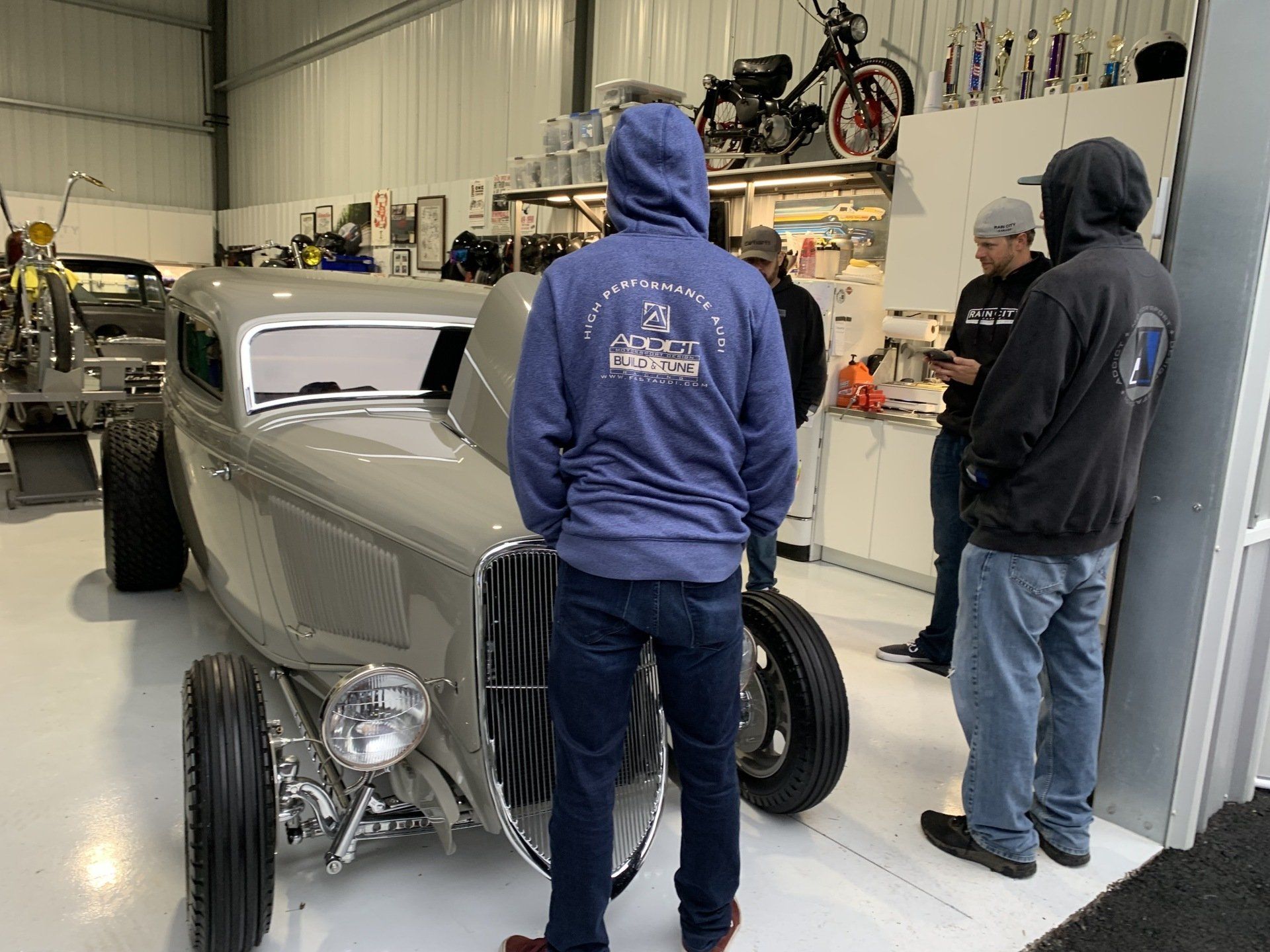 Classic silver hot rod in a garage with two people standing beside it
