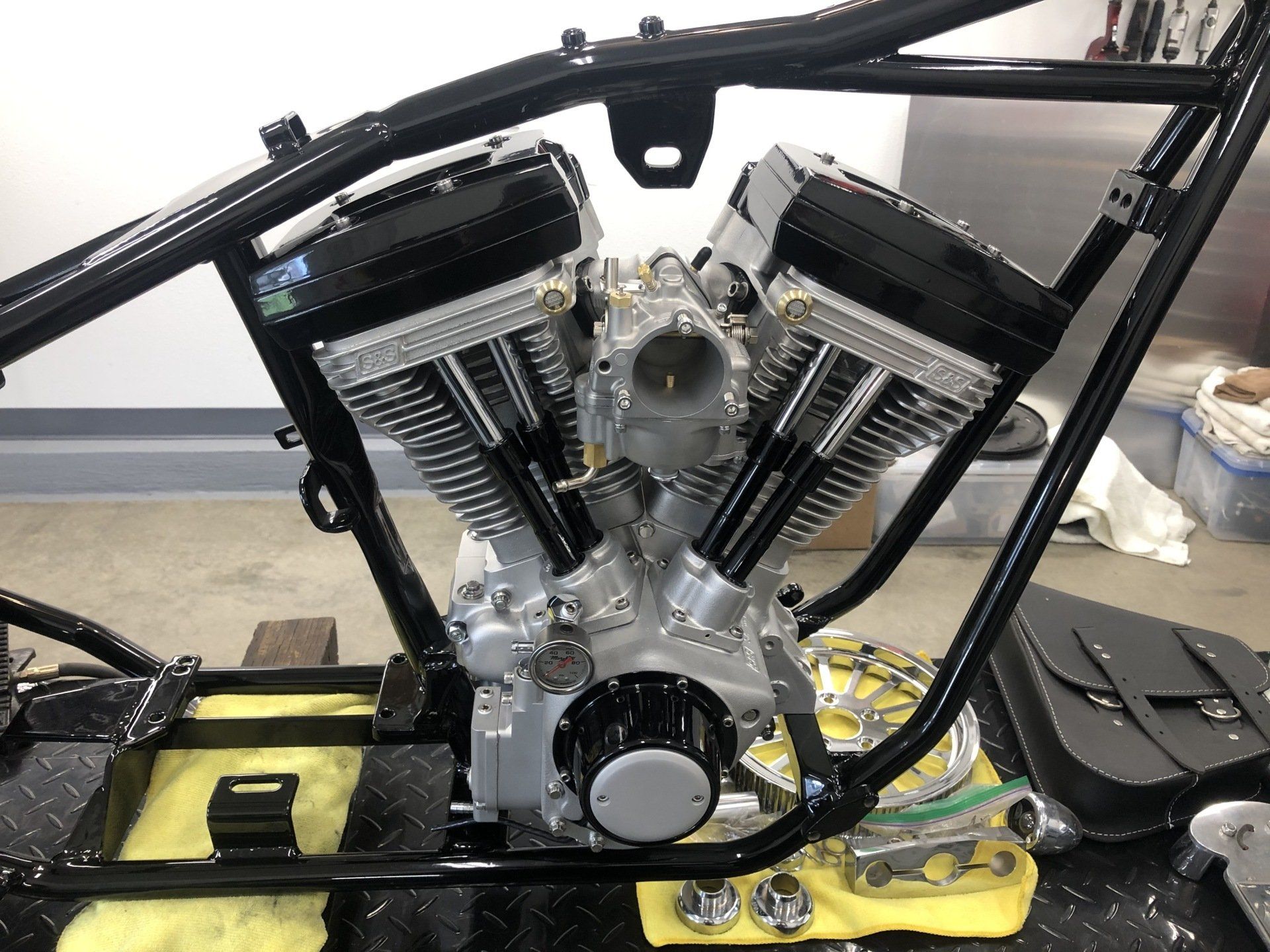 Custom V-twin motorcycle engine mounted in a black frame on a workbench with tools nearby