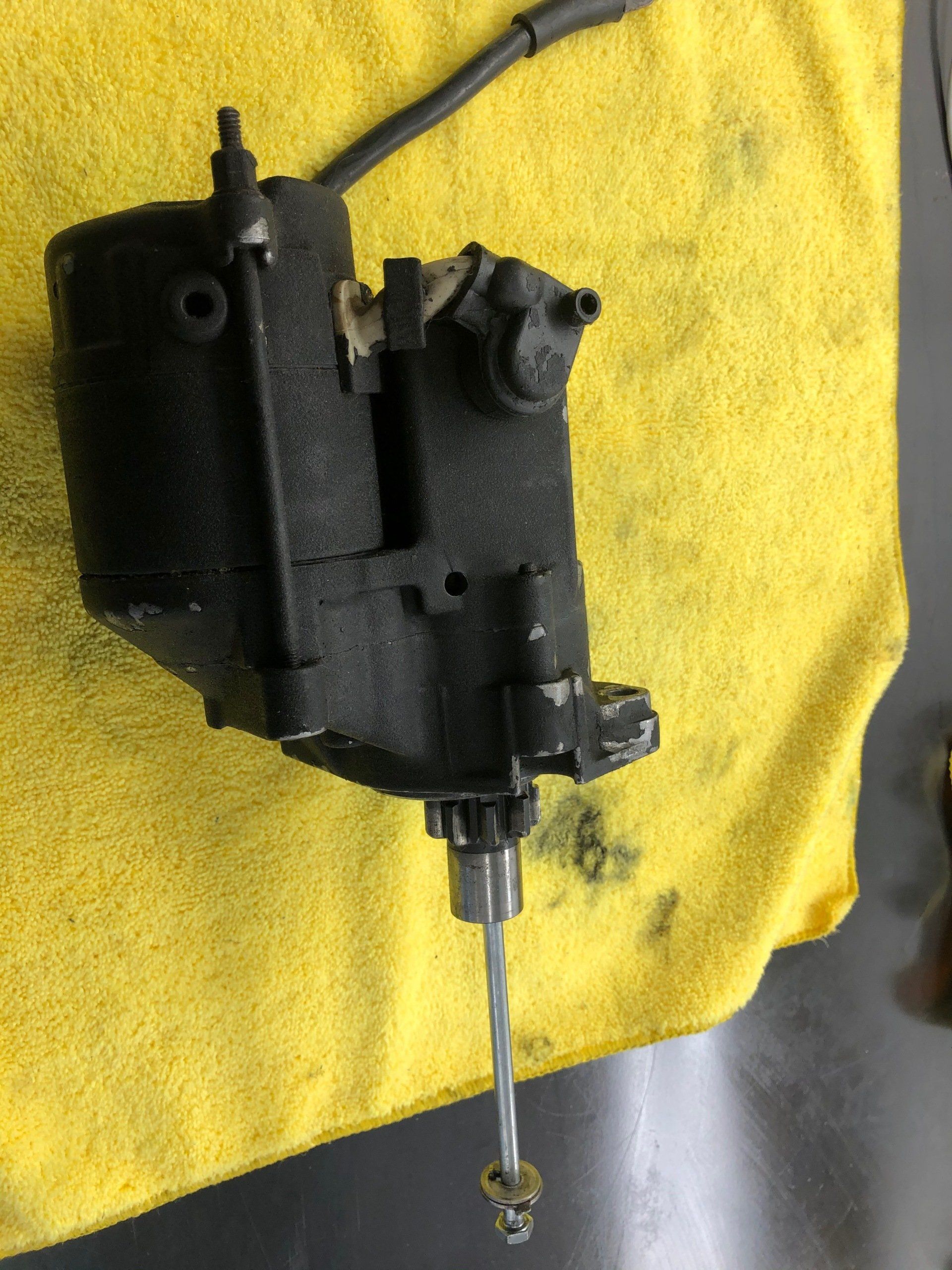 Black mechanical part with a metal rod on a yellow cloth background