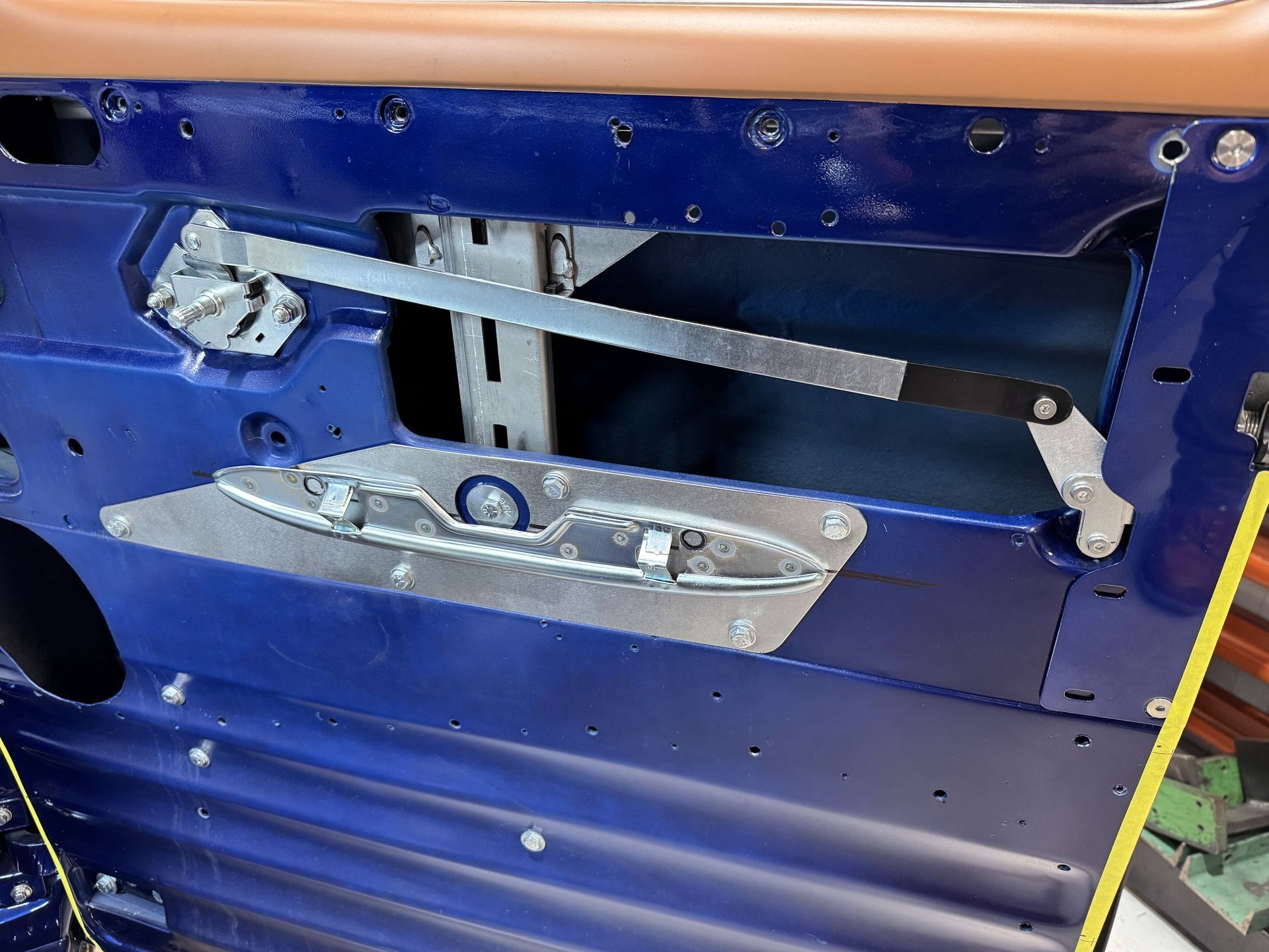 Blue car door interior with exposed window regulator and metal mounting panel