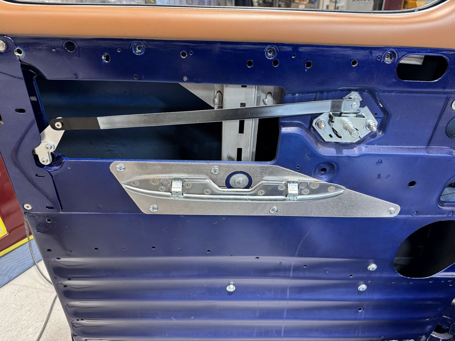Blue car door interior with exposed window mechanism and silver handle panel