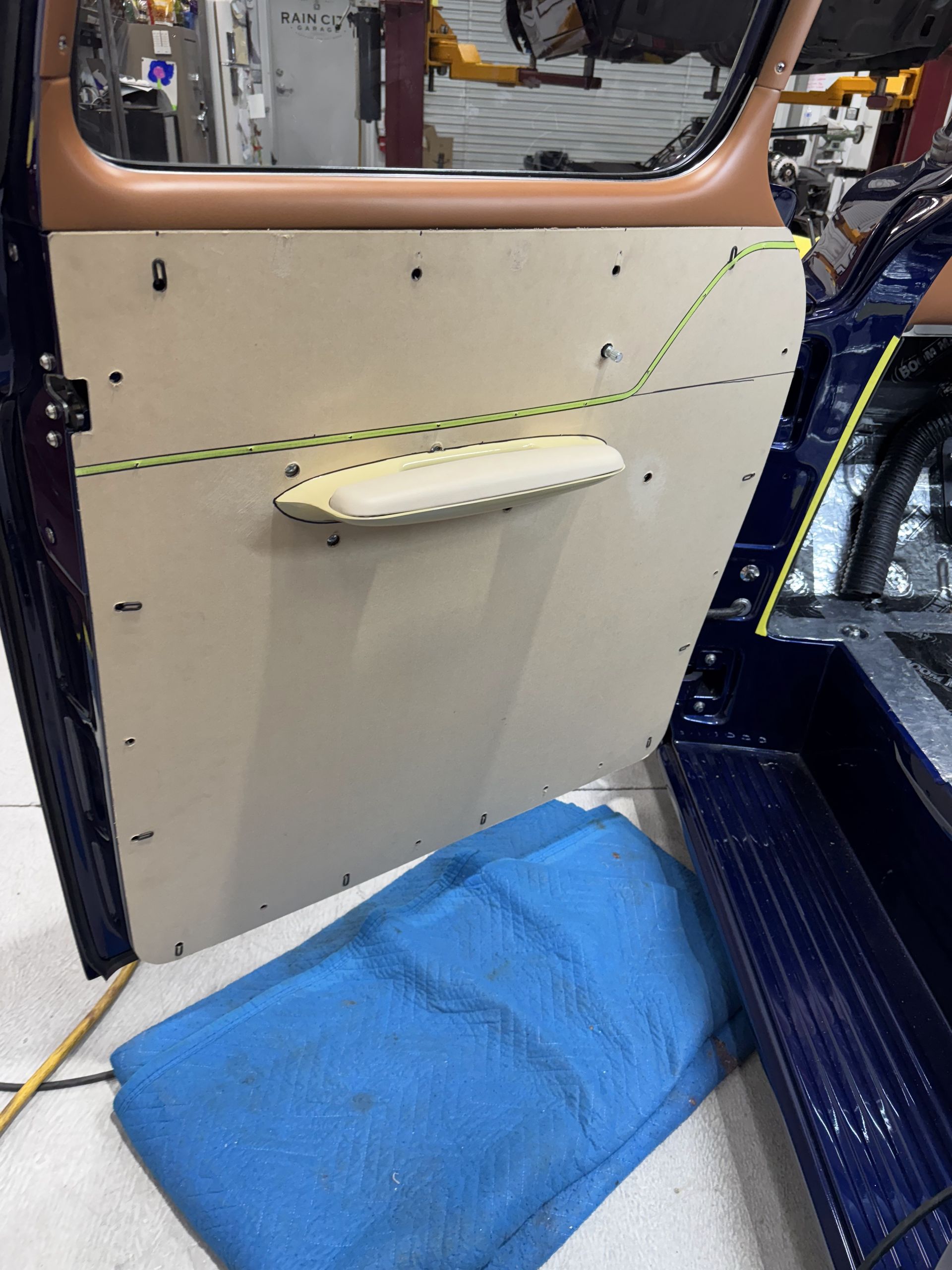 Interior of an aircraft door with a cream handle, blue floor mat, and green marked tape lines.