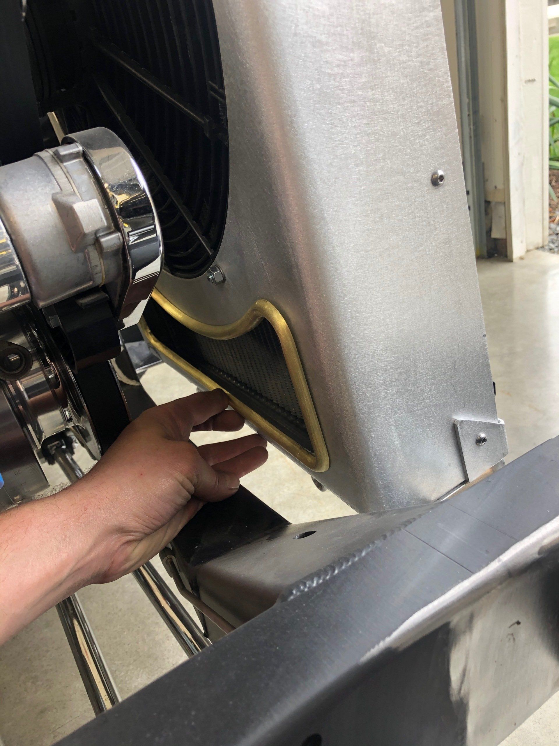 Hand reaching into an industrial machine, adjusting a black panel with yellow trim.