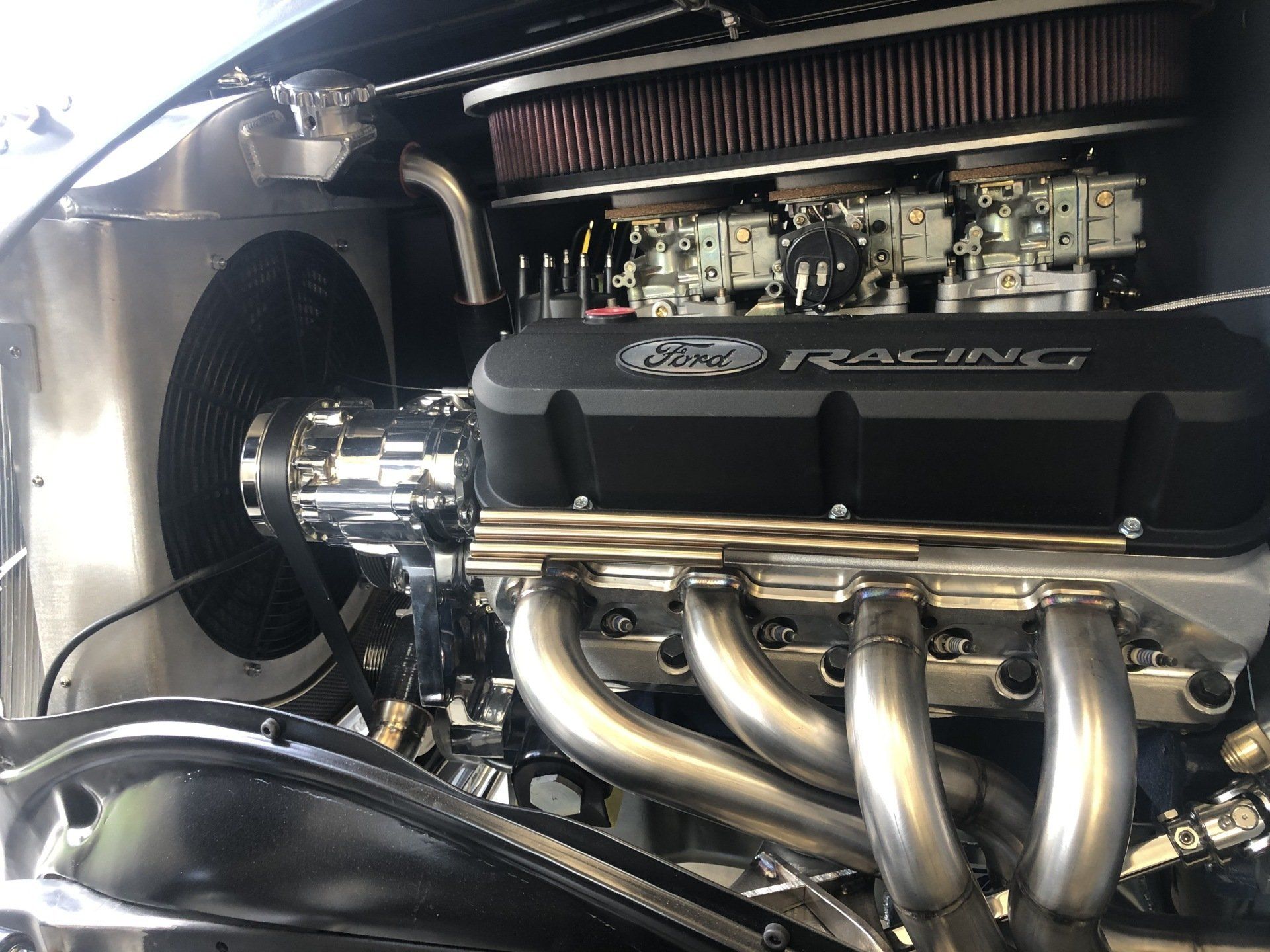 Close-up of a car engine bay with polished intake and chrome exhaust headers.