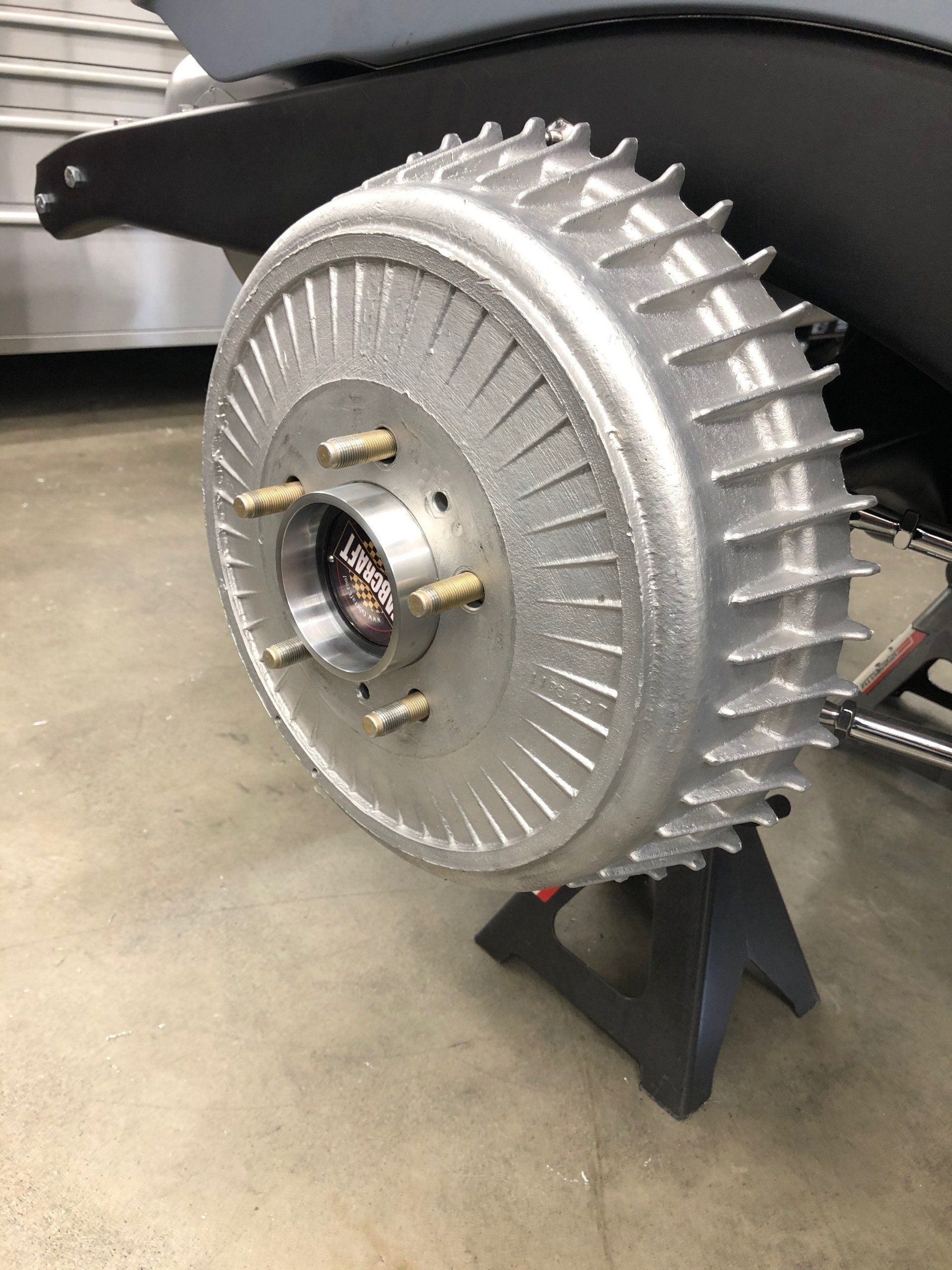 Large silver industrial fan or blower with a black handle, mounted on a stand indoors.