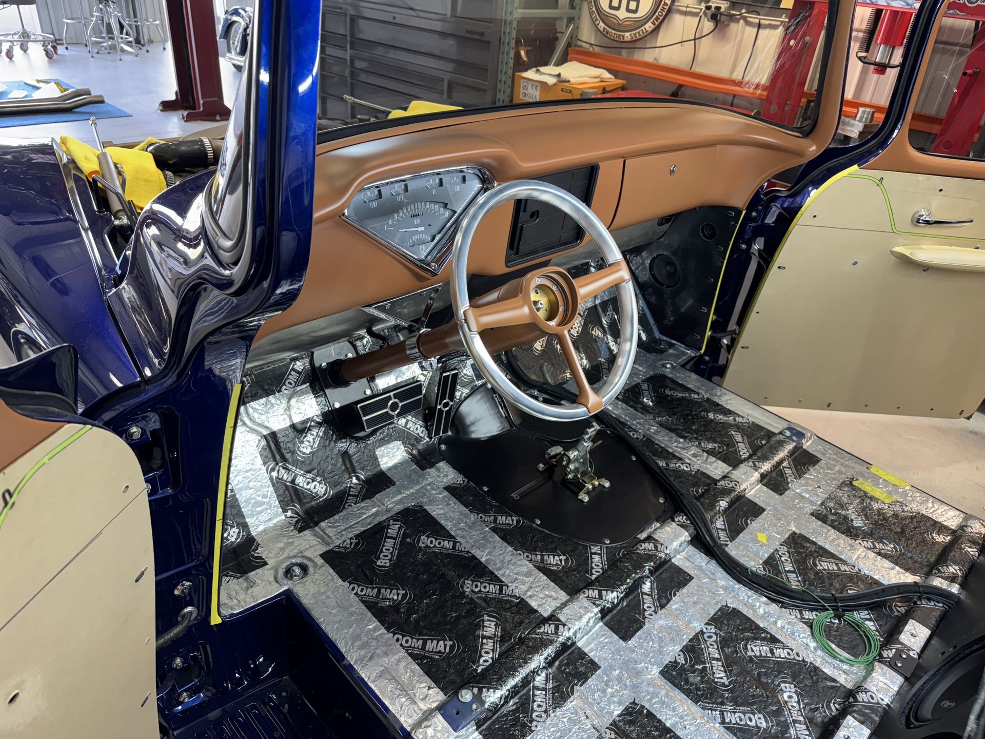 Interior of a stripped car under repair, with exposed dashboard, steering wheel, and bare floor panels