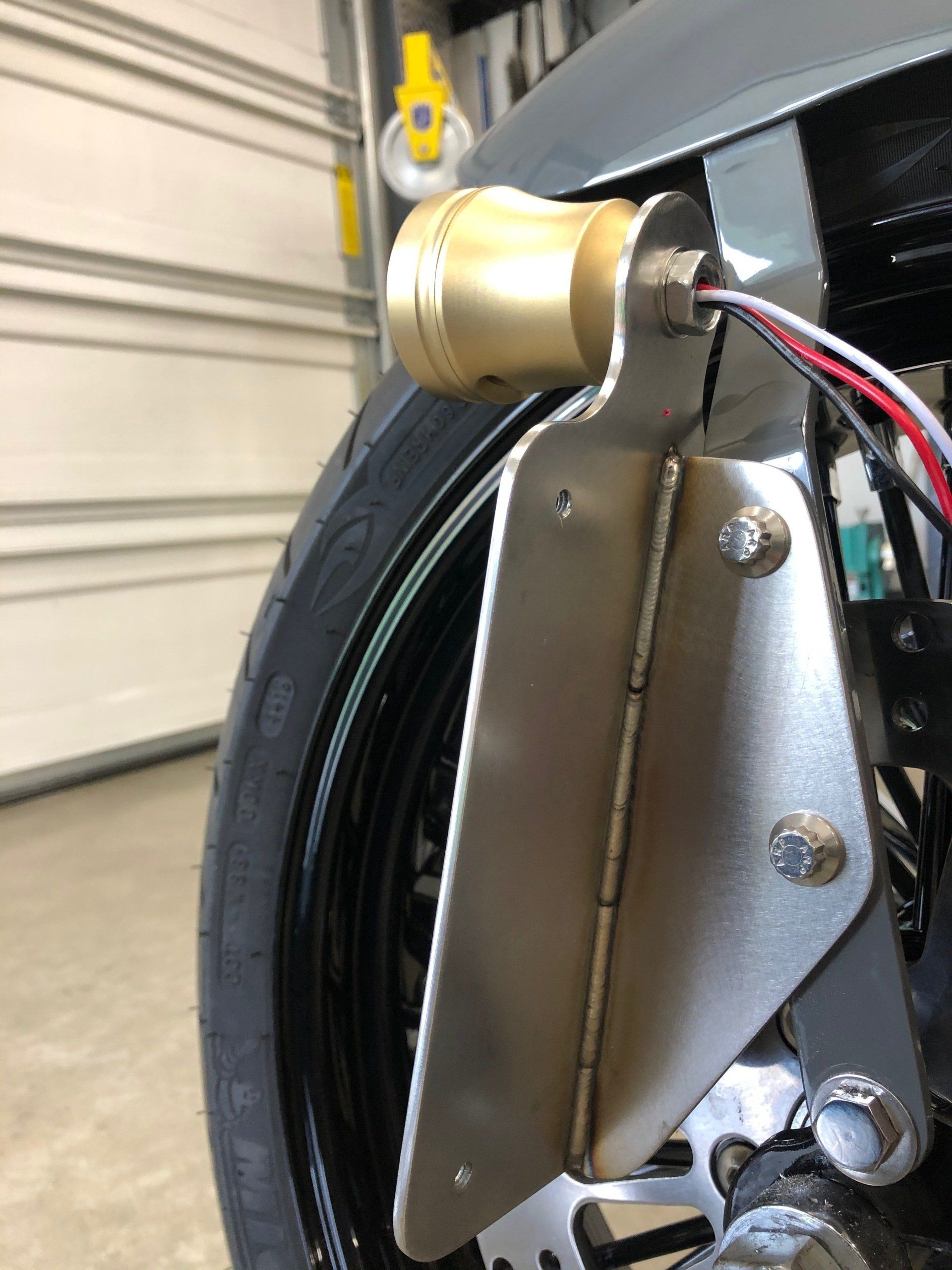Close-up of a wheel hub motor with metal mounting bracket and visible red, white, and black wires.