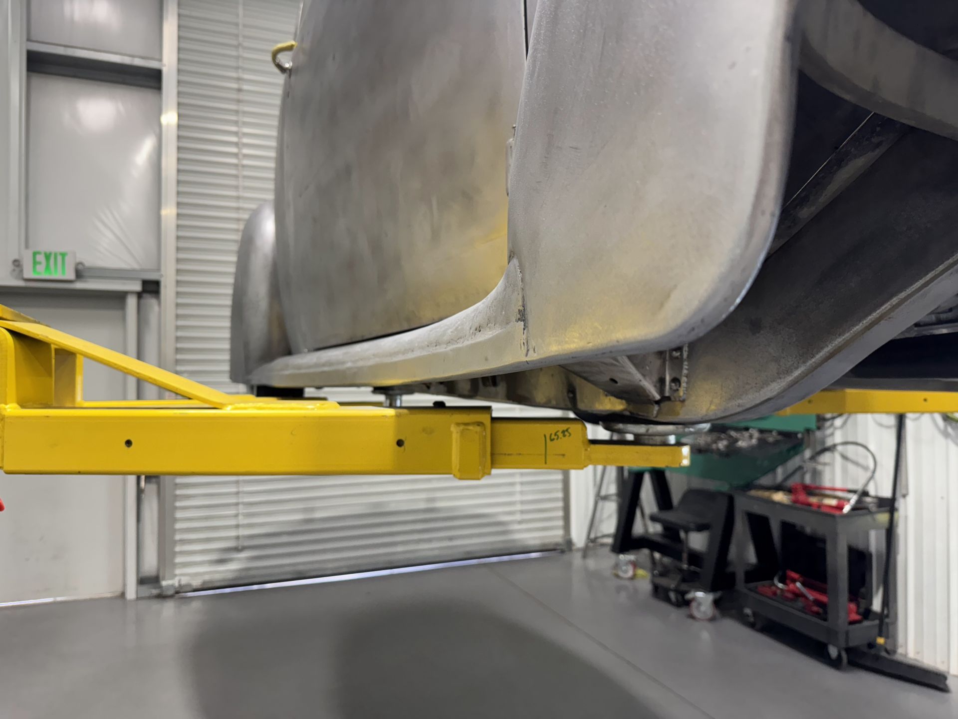 Yellow lift platform beneath large metal equipment inside an industrial warehouse
