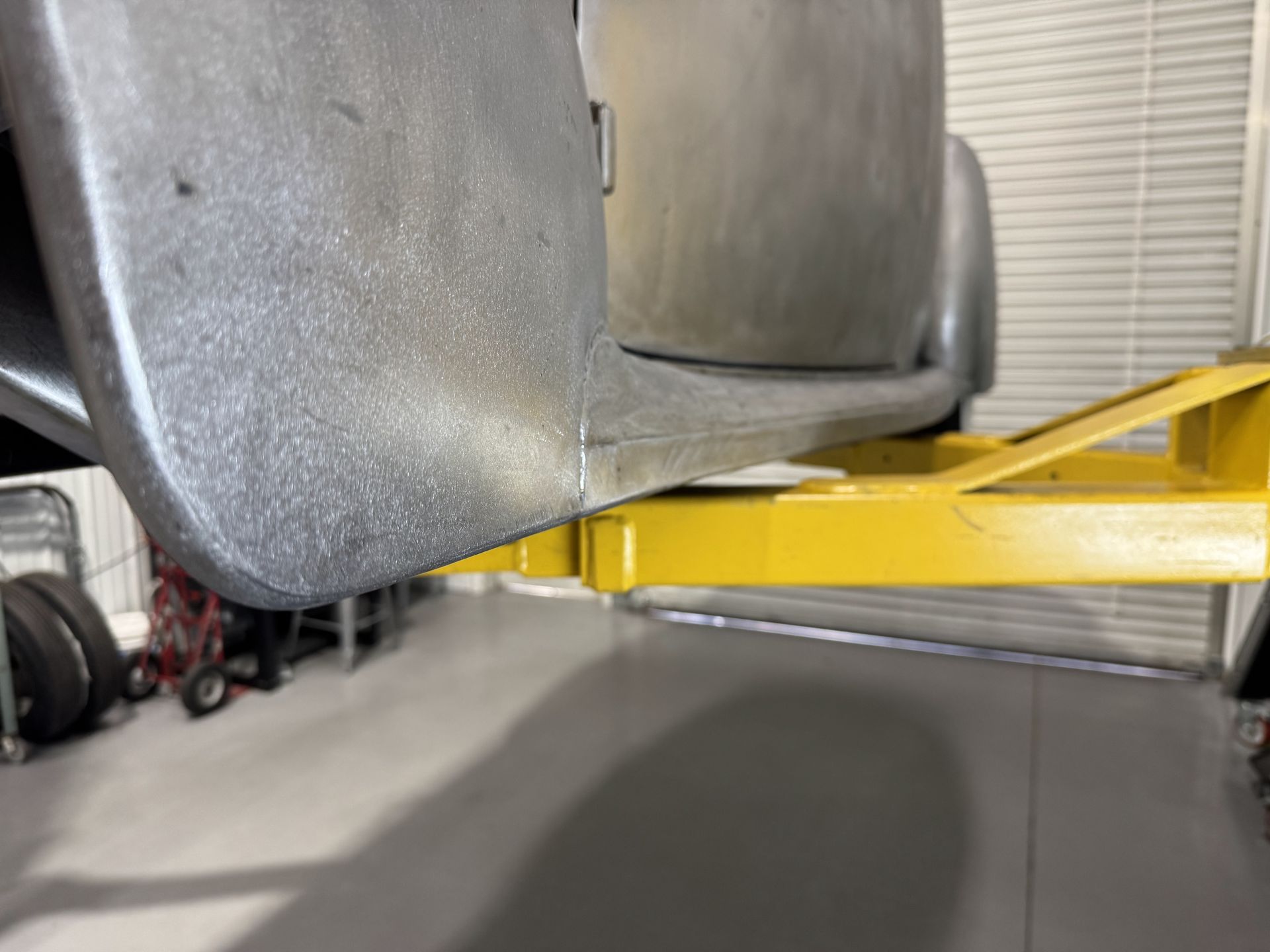Yellow car lift arm supporting a gray vehicle in a garage or workshop