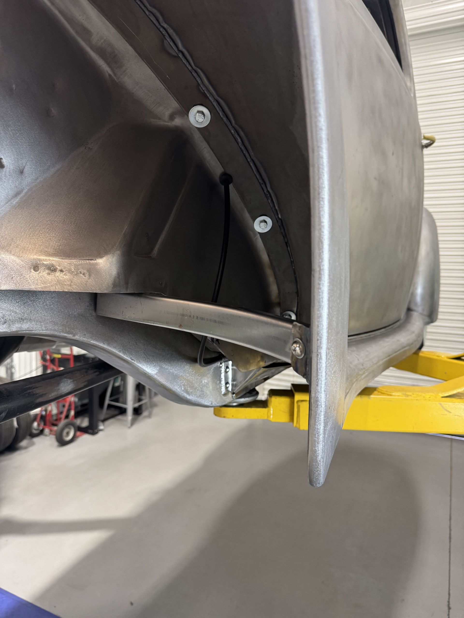 Close-up of a damaged car bumper and wheel arch on a lift in an auto repair shop