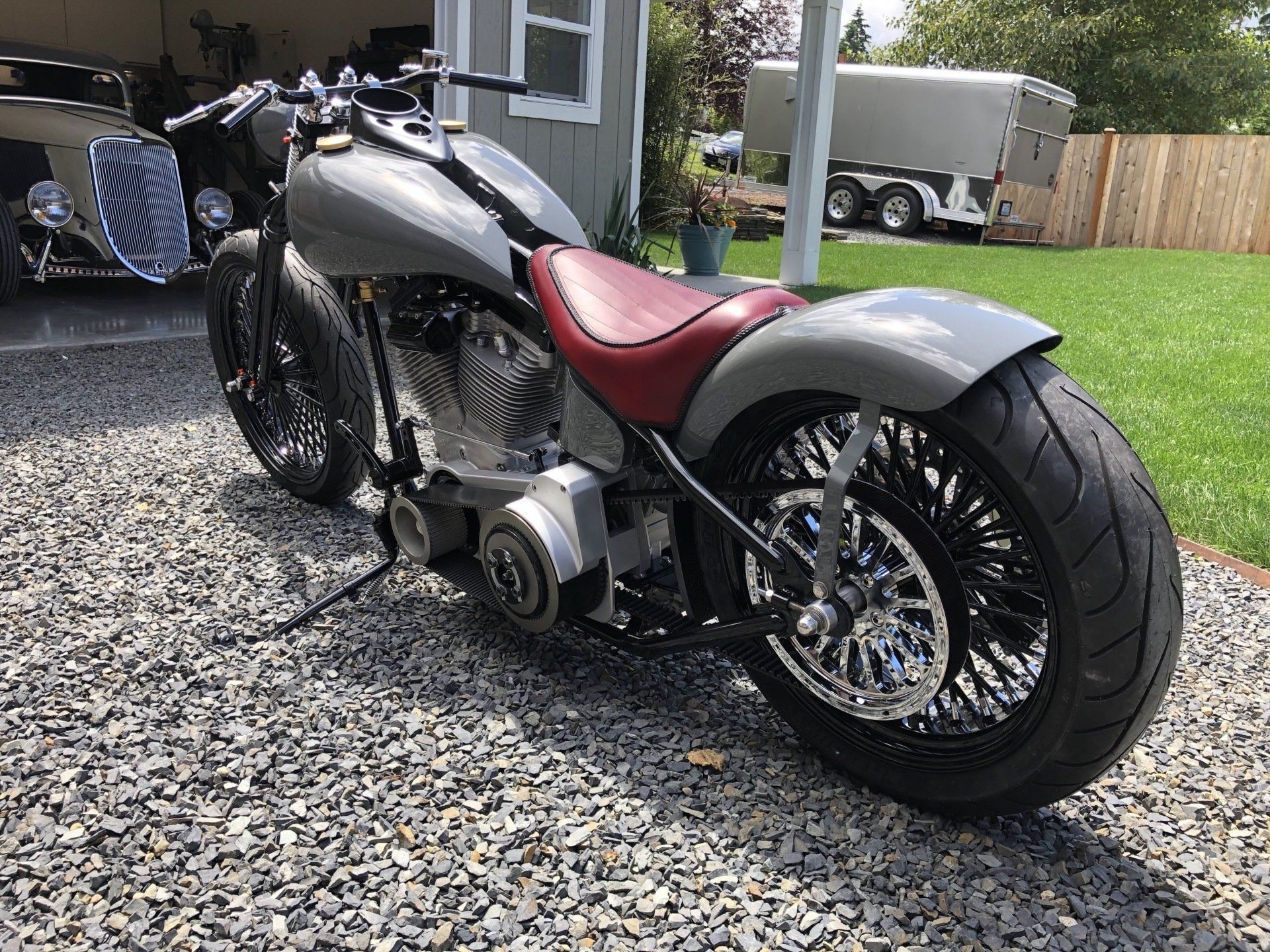 Custom gray and red motorcycle parked on gravel driveway beside a house